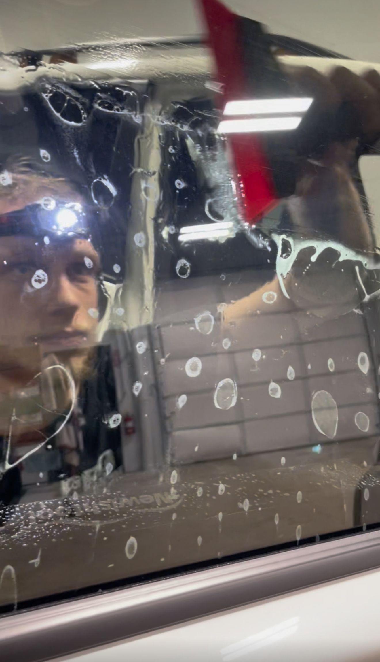 A person is applying a clear film to the hood of a car.