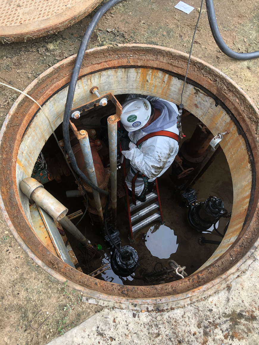 A manhole cover with a man standing inside of it.