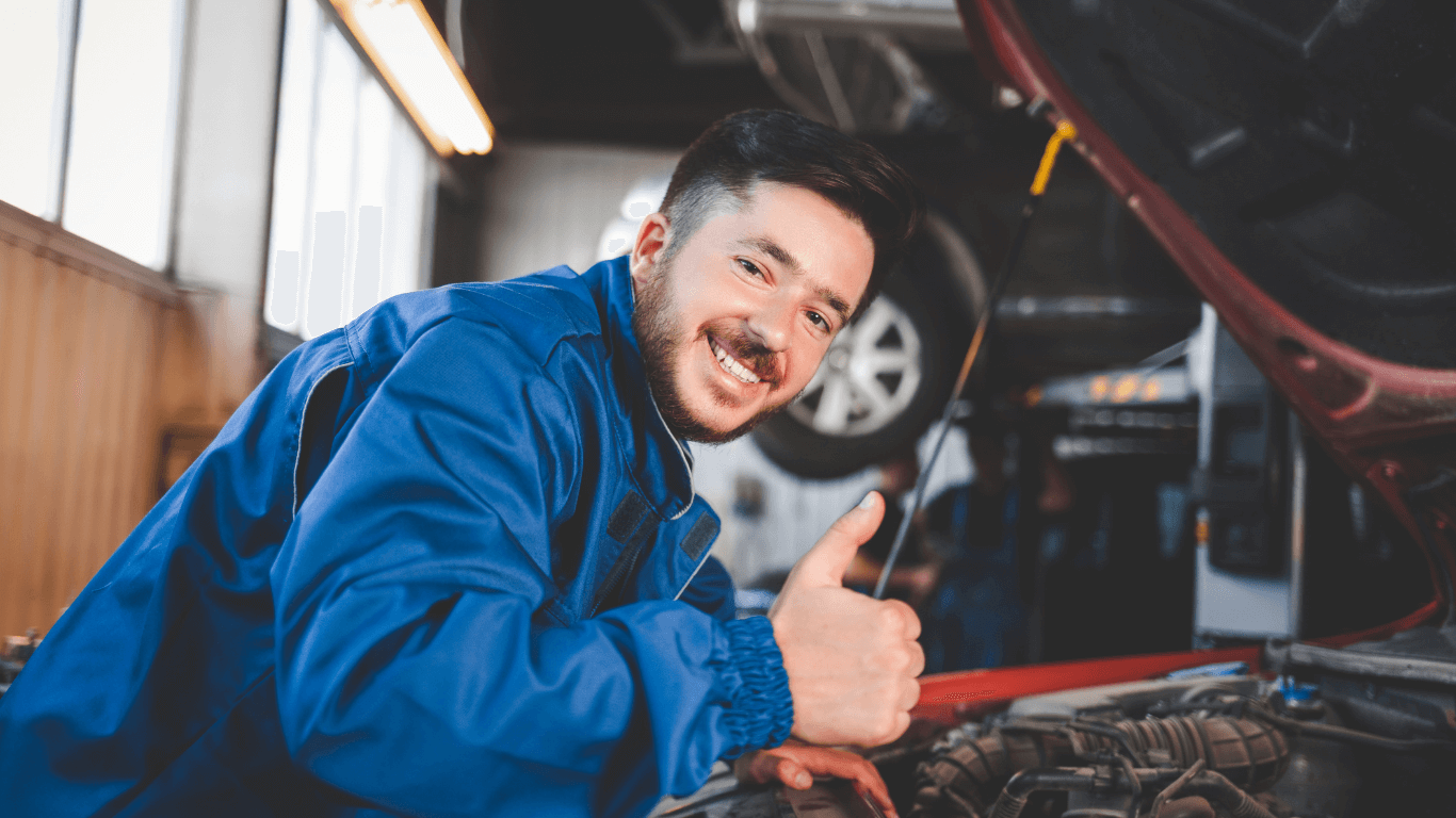 a smiling mechanic under the hood of a car