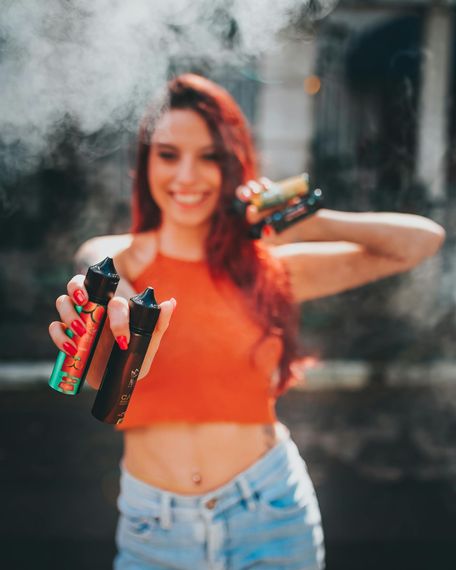 Woman holding vape liquid bottles. 