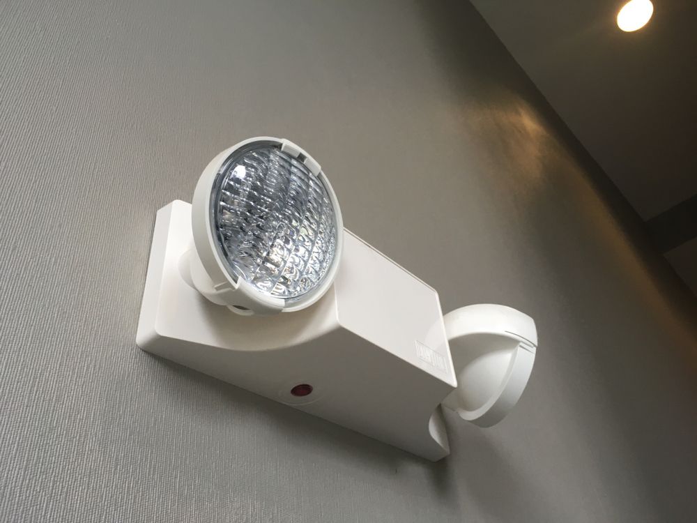 A white emergency light is mounted to a gray wall