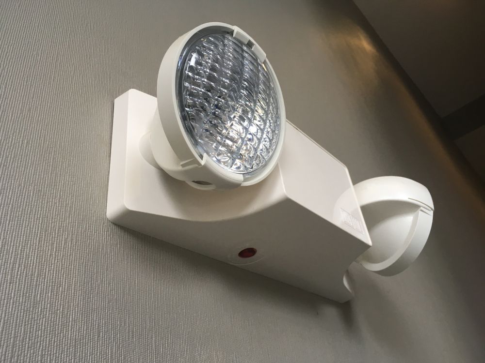 a white emergency light is mounted to a wall.