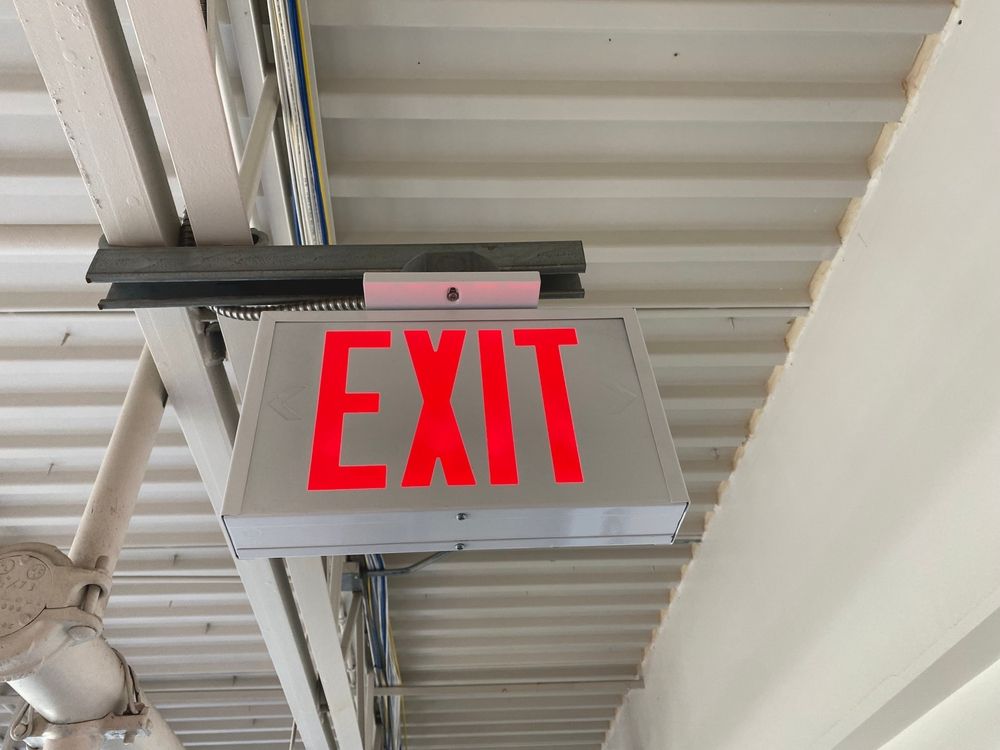 A red exit sign is hanging from the ceiling of a building.