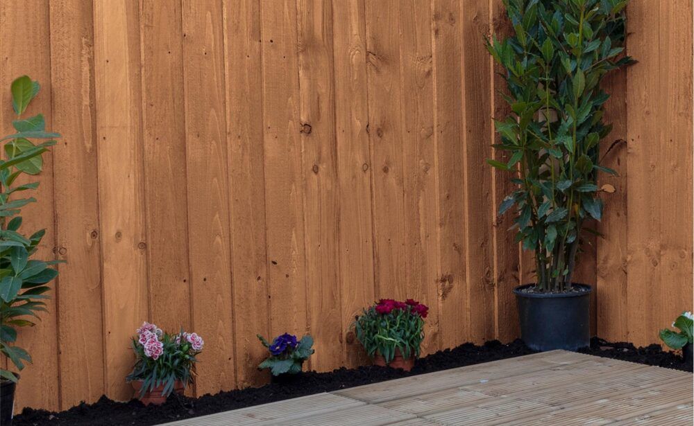 Brown wooden fence with potted plants and flowers.