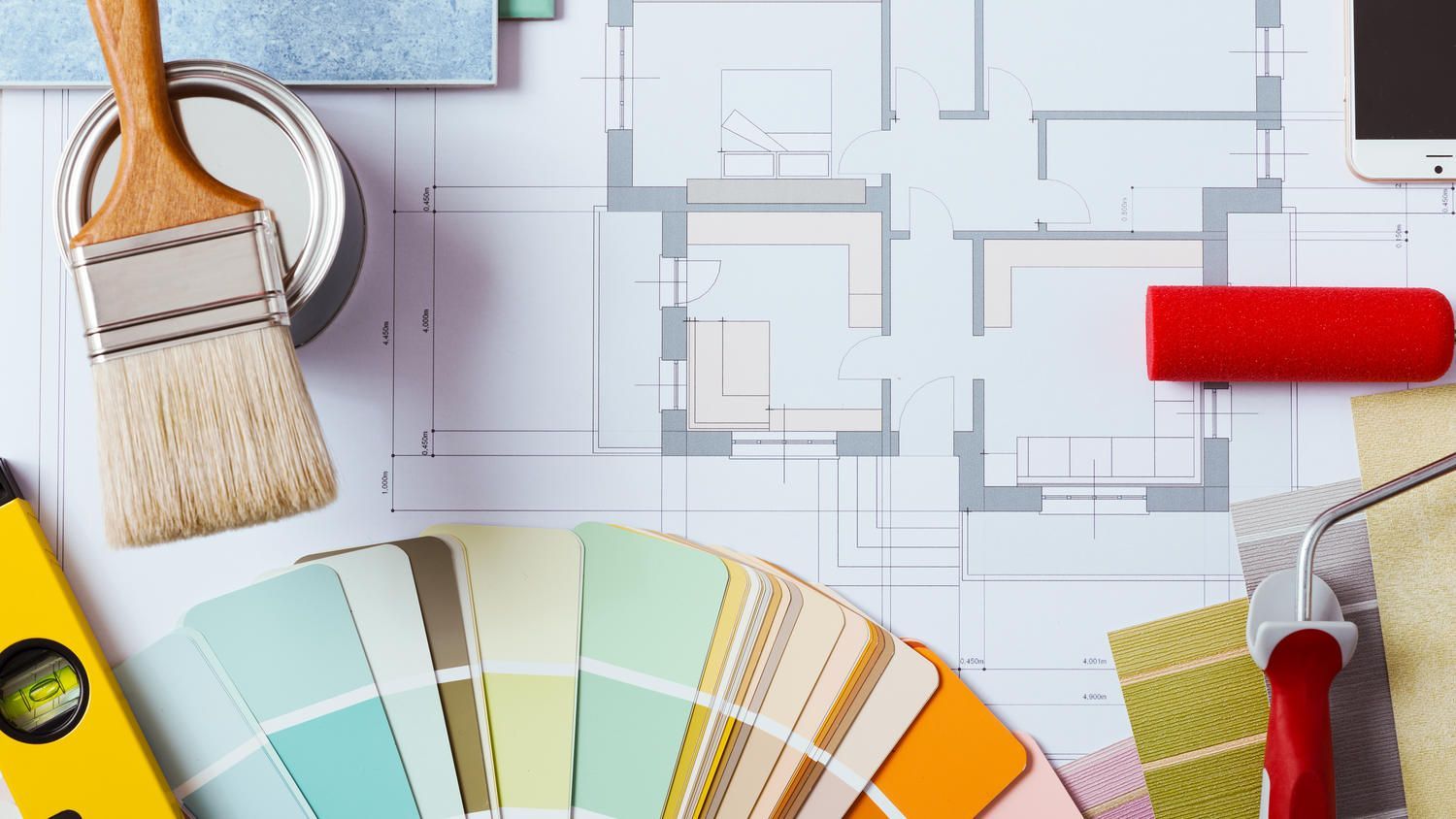 Paintbrushes, paint can, color swatches, and blueprints for home renovation.
