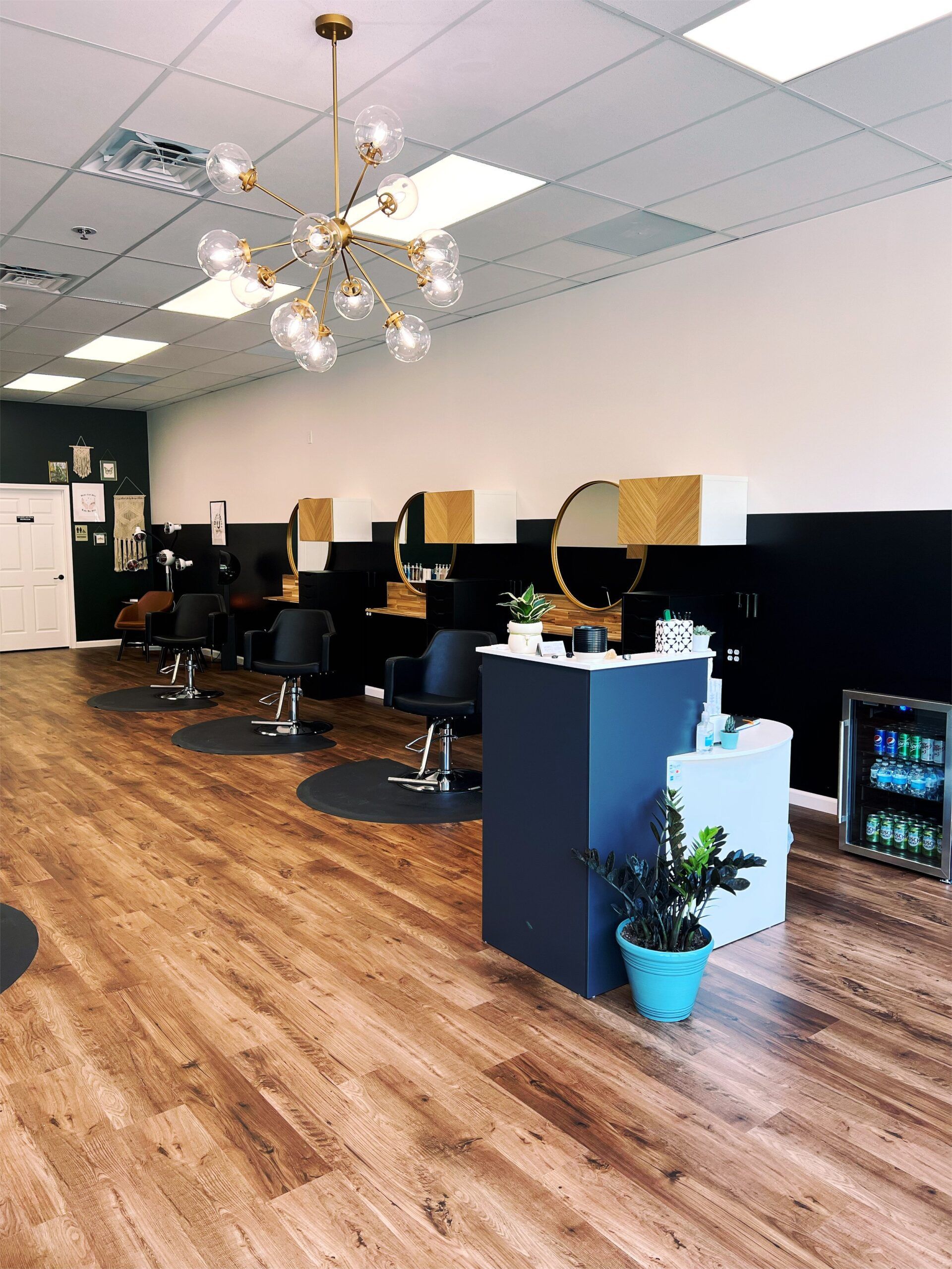Hair salon interior with styling stations, wooden floors, and a blue and gold color scheme.