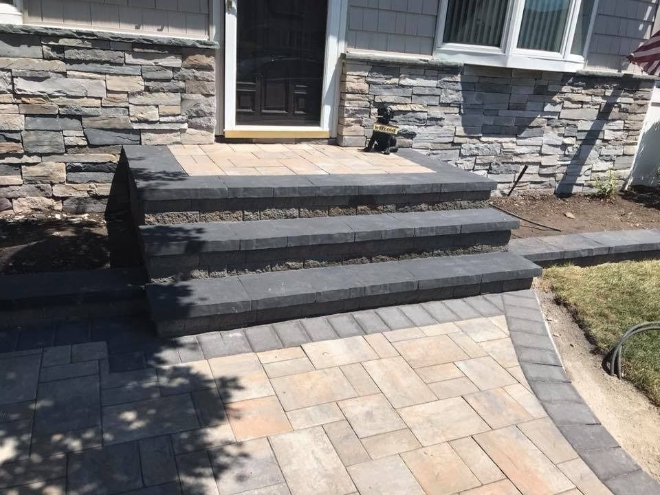 Stone steps leading up to a house entrance with paver walkway.