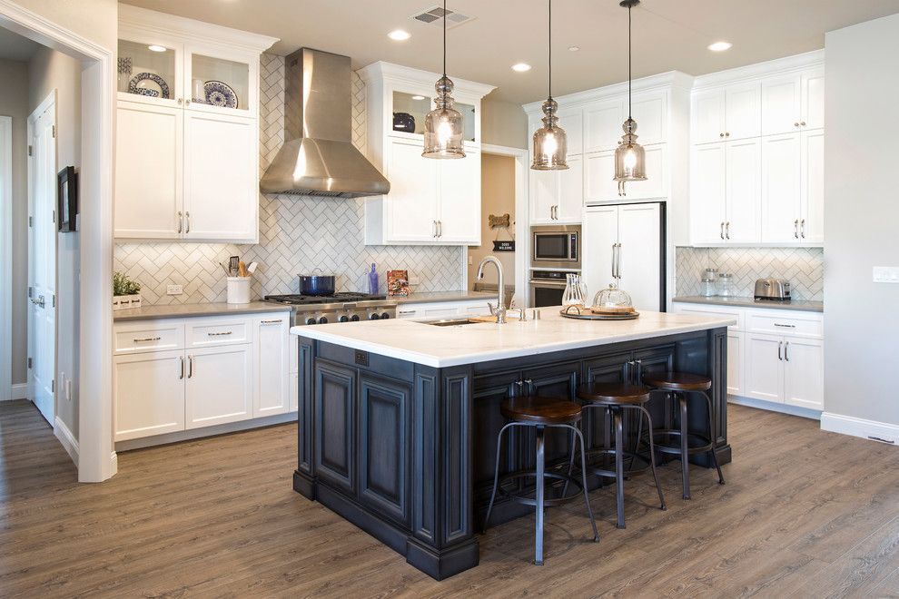 Kitchen with white cabinets, dark blue island, stainless steel appliances, and wooden floor.
