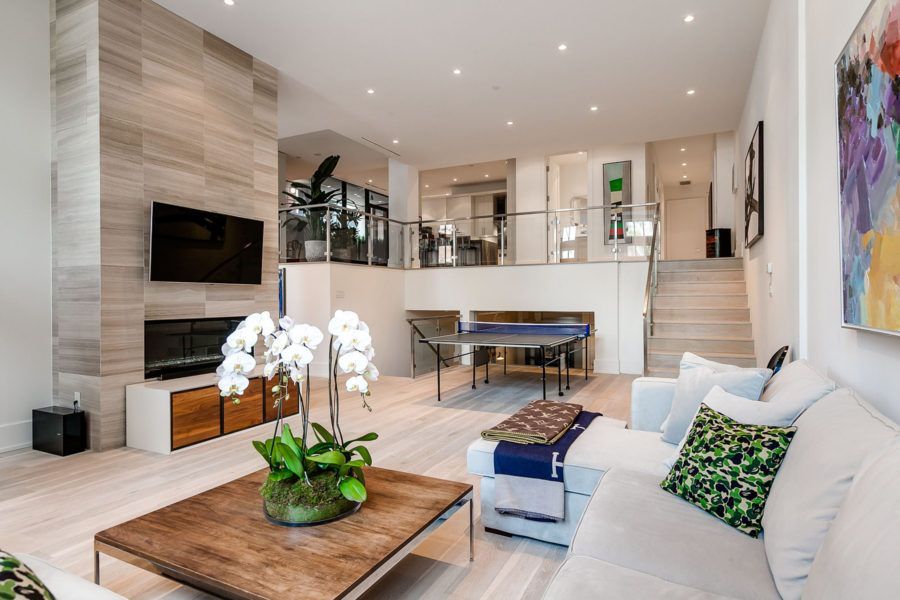 Modern living room with fireplace, white couches, and ping pong table.