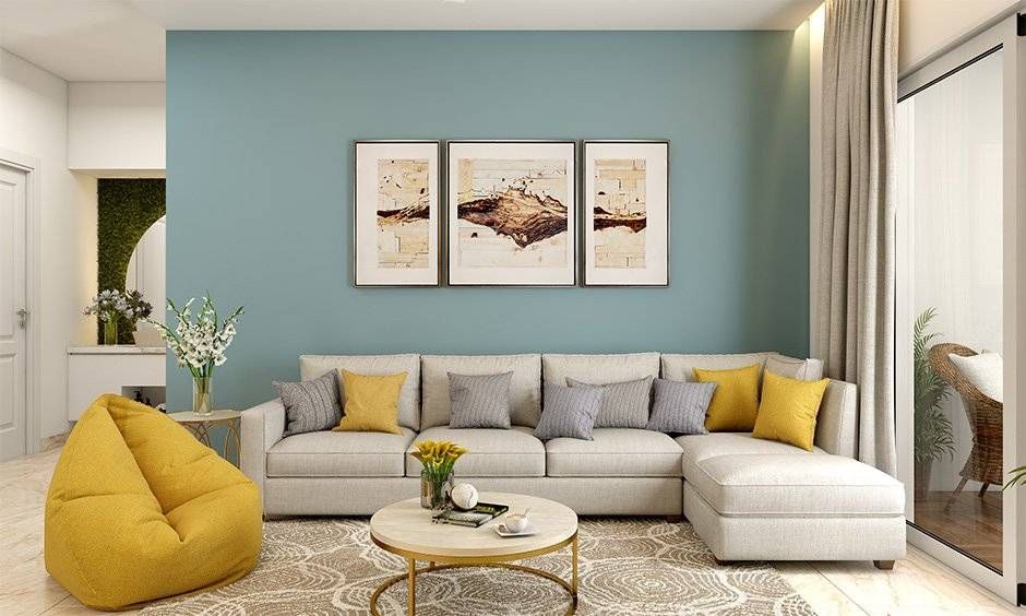 Living room with blue wall, sectional sofa, and yellow accents; art and beanbag.