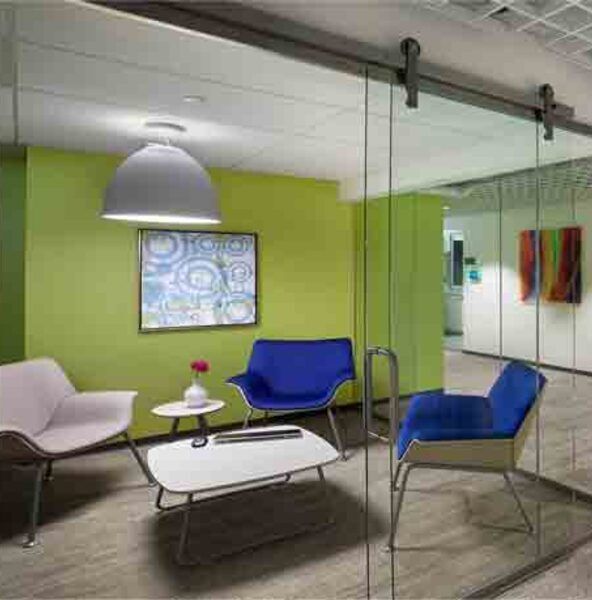 Modern waiting area with lime green walls, glass sliding door, and colorful chairs.
