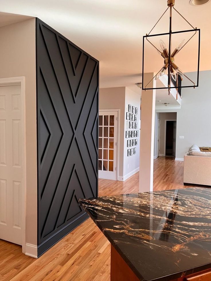 Black geometric accent wall in a kitchen with wooden floors.