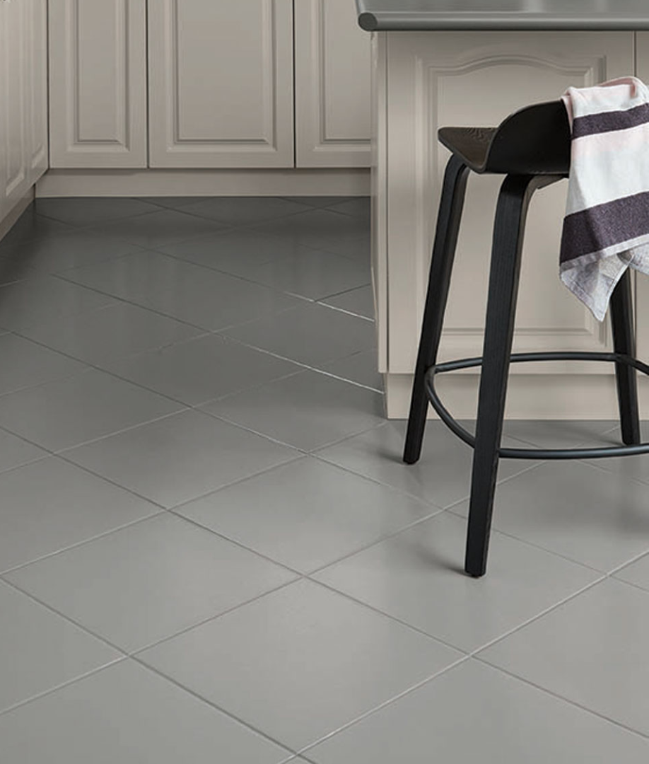 Gray tiled kitchen floor with a black stool and a hanging towel.