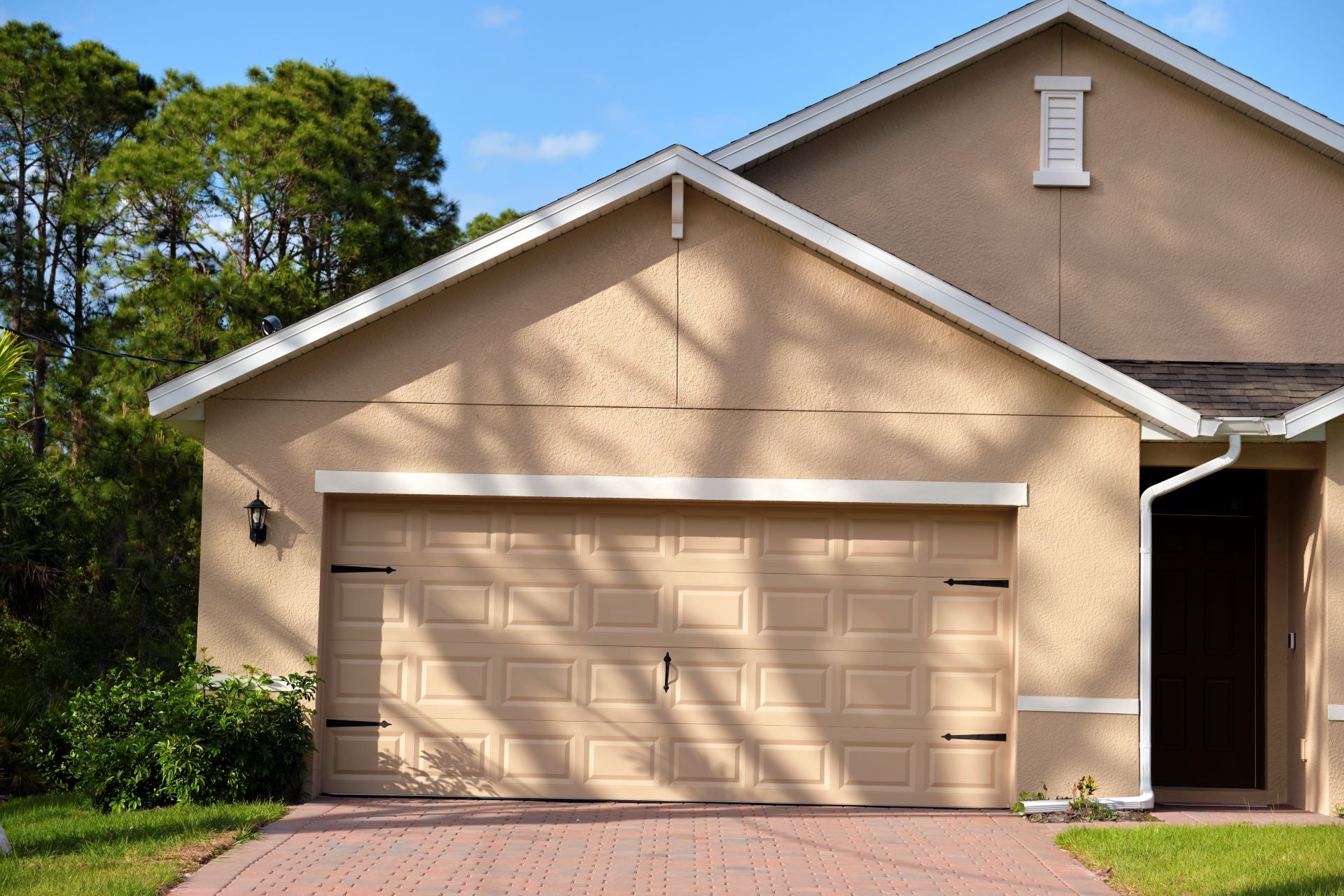 A house with two garage doors and a brick driveway