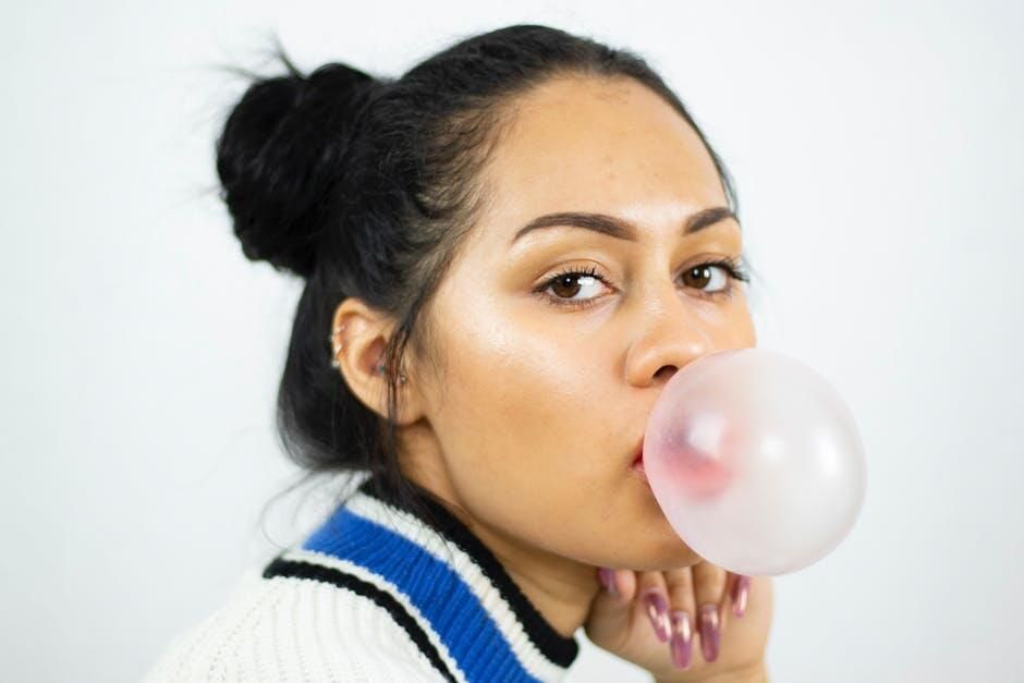 A woman is blowing a bubble of gum in her mouth.