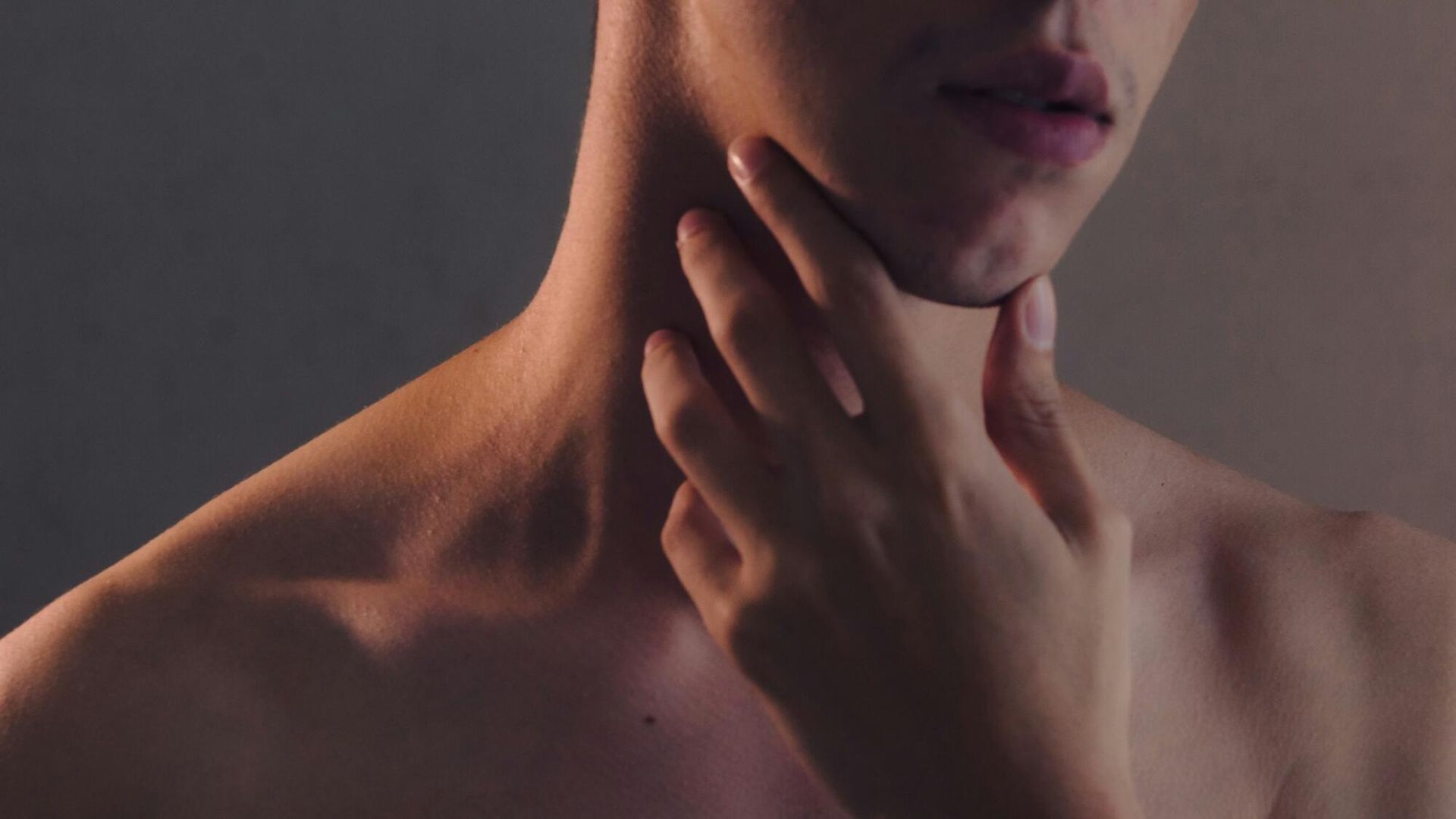 A close up of a person 's neck with their hand on it.