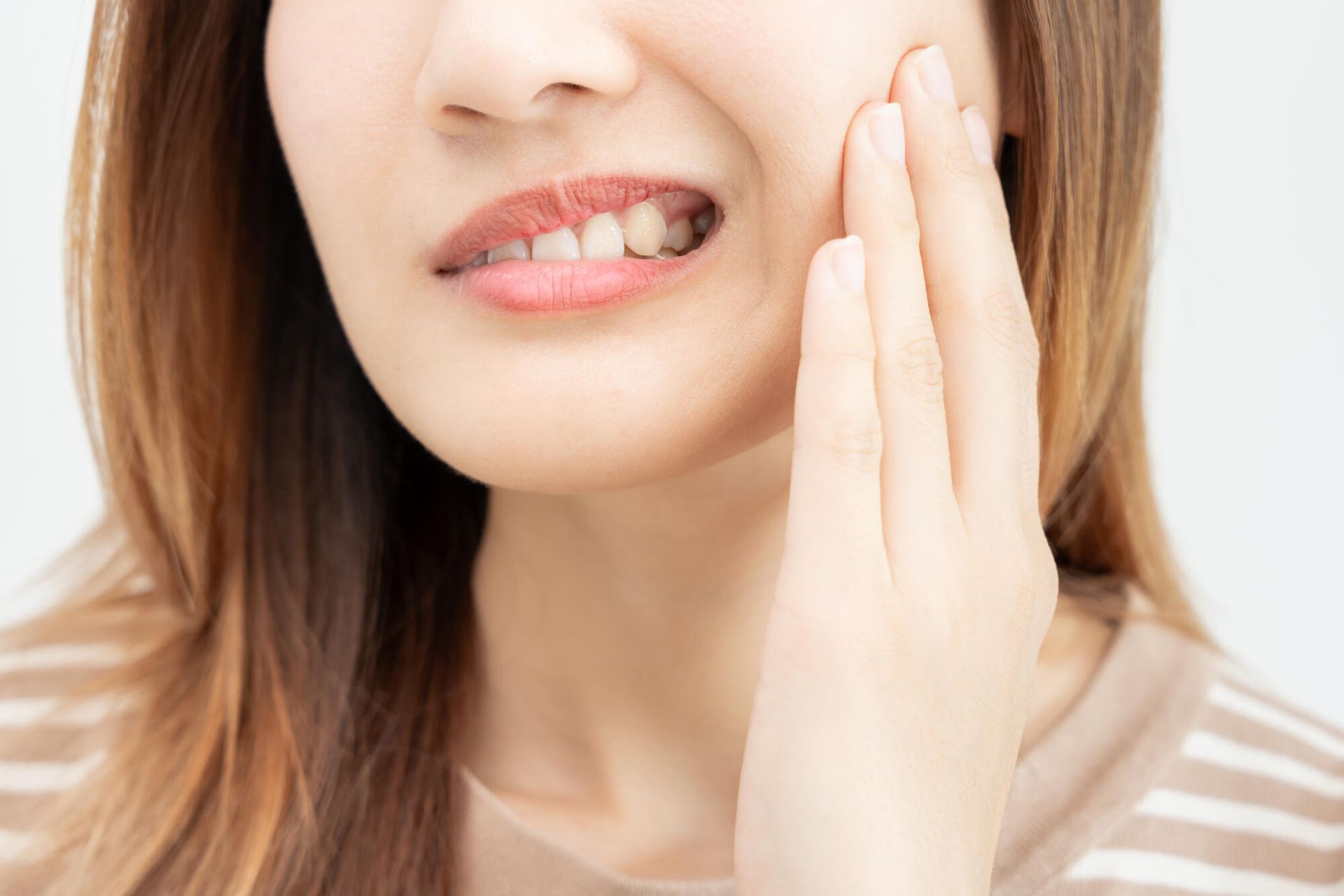 A woman is holding her face in pain because of a toothache.