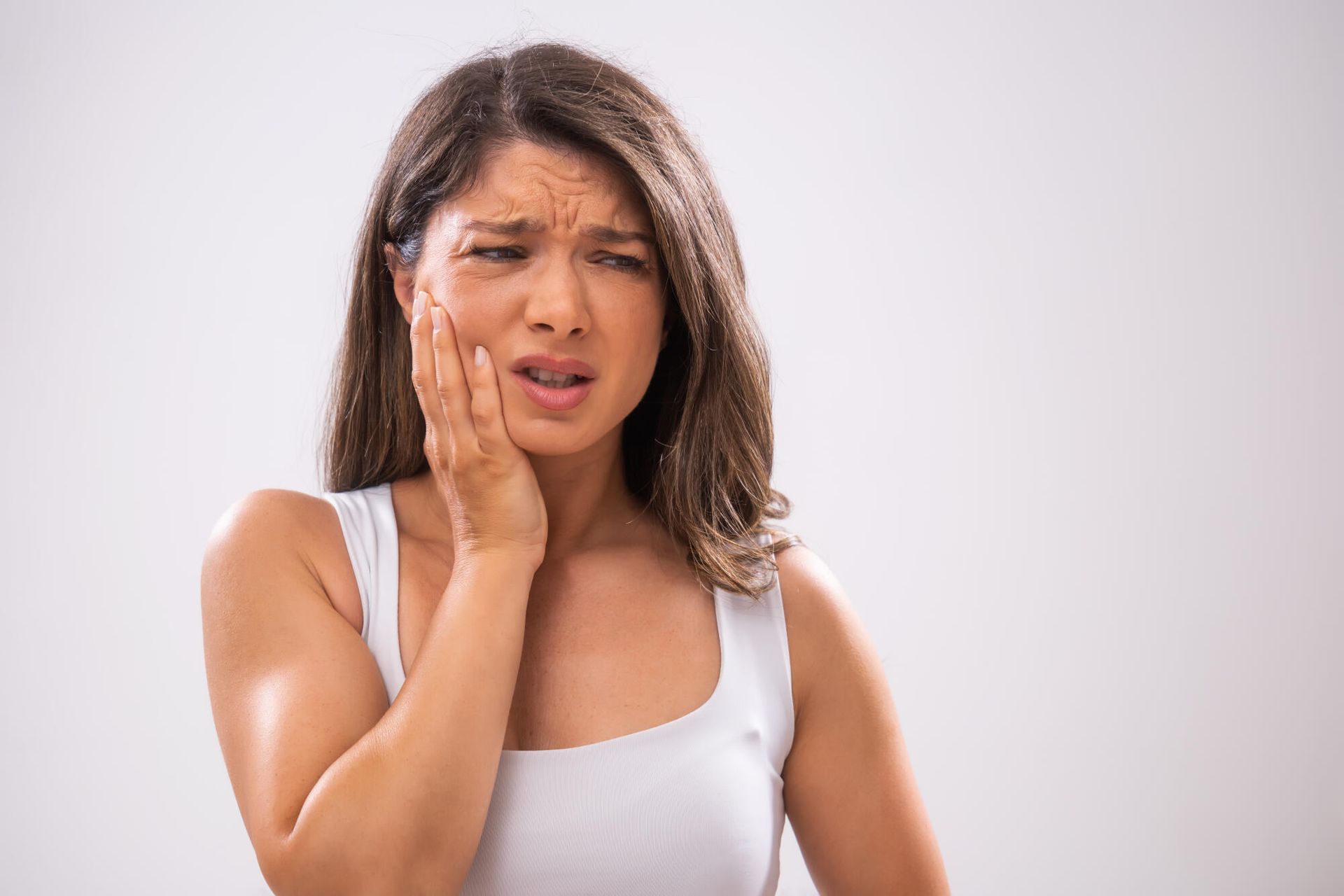 A woman is holding her face in pain because of a toothache.