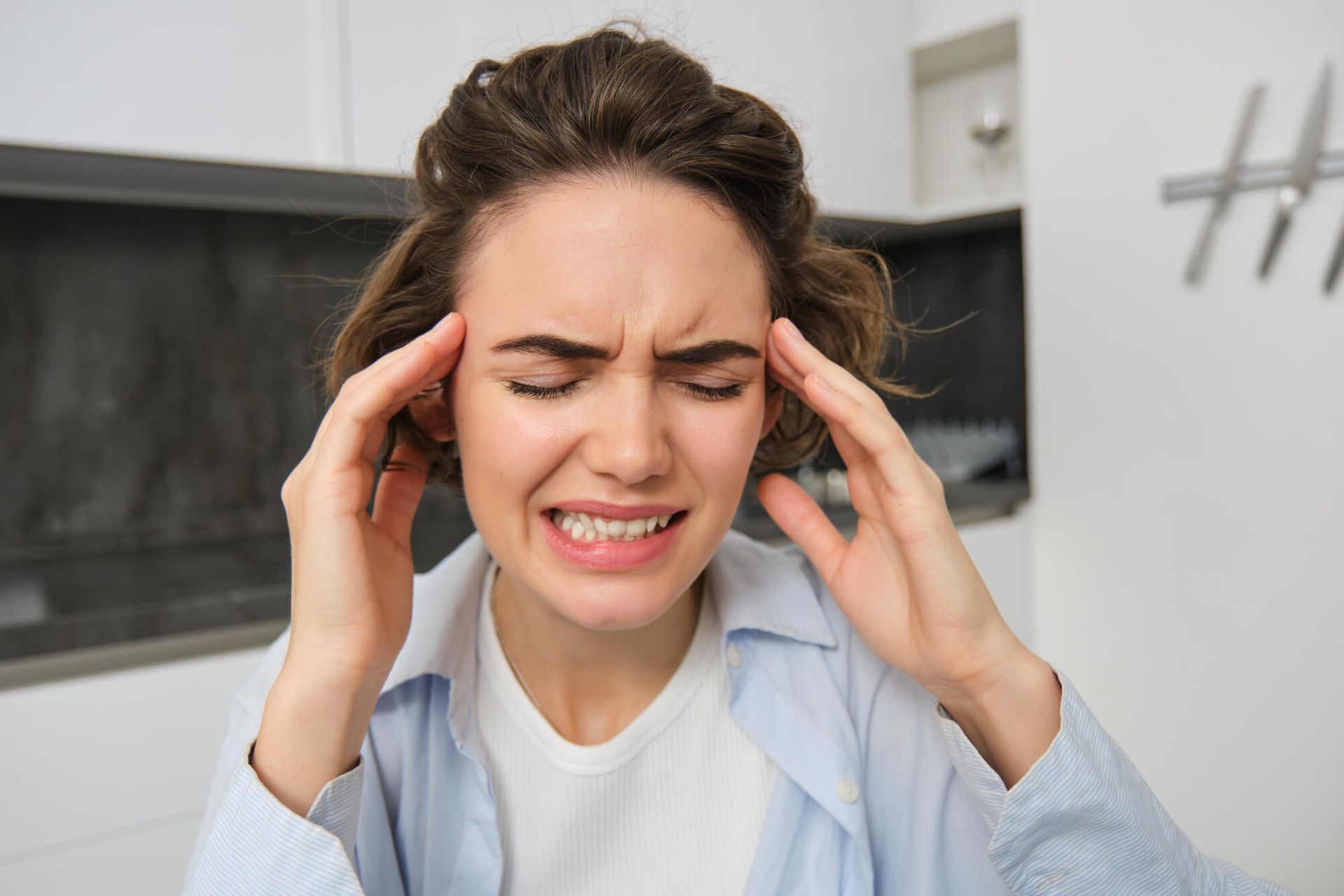 A woman is holding her head because she has a headache.