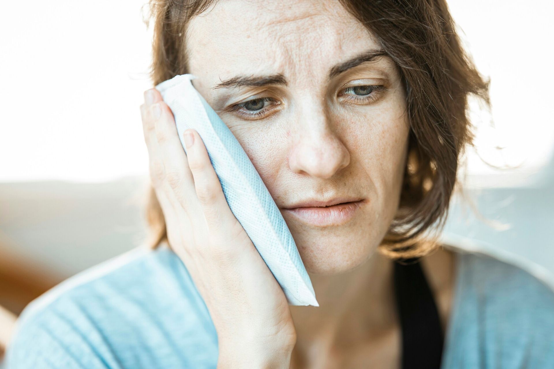 a woman has a toothache and is holding a towel to her face