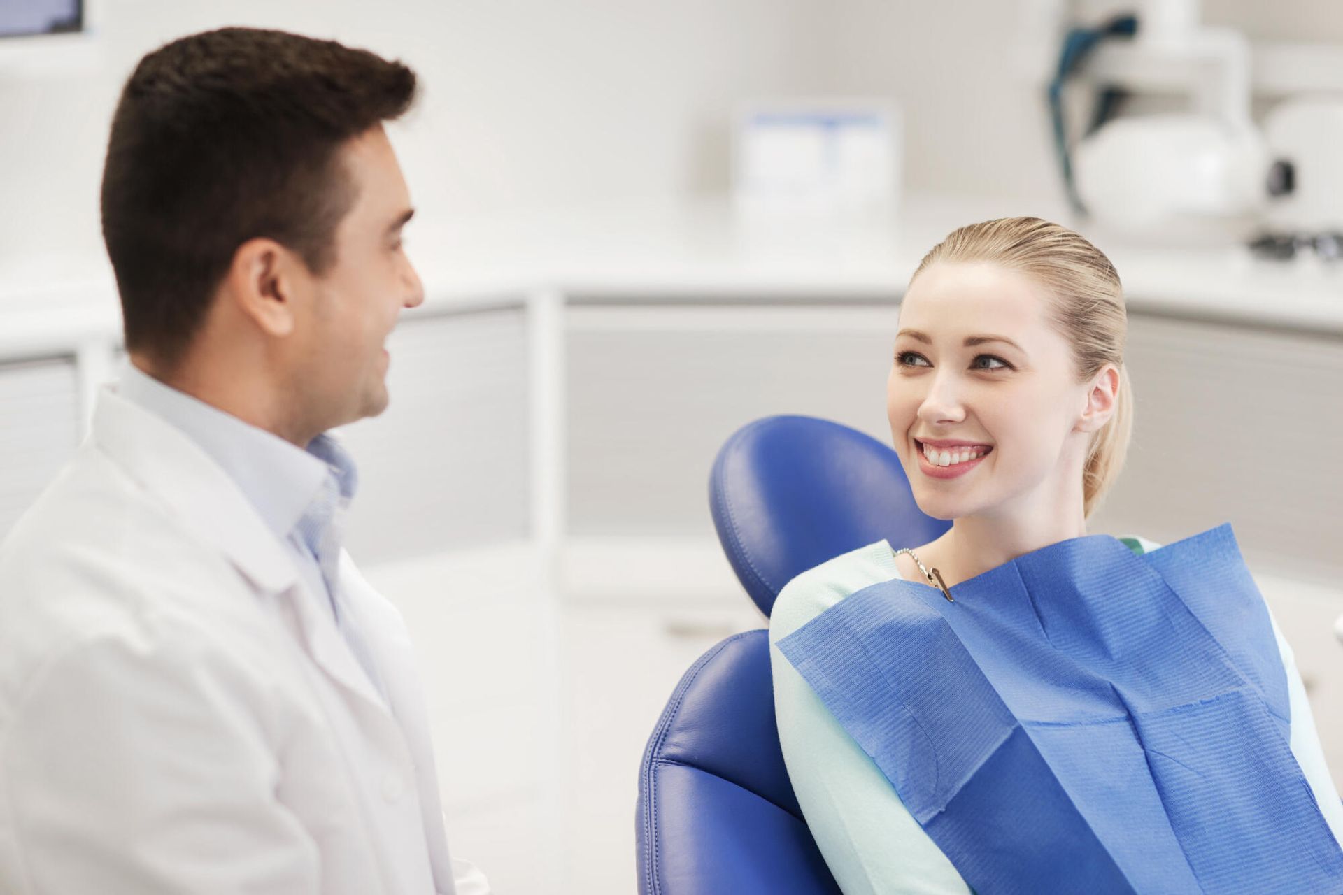 A woman is sitting in a dental chair talking to a dentist.