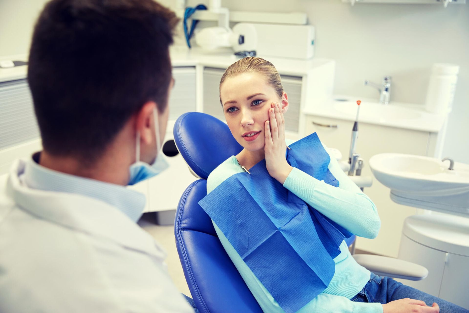 A woman is sitting in a dental chair talking to a dentist.