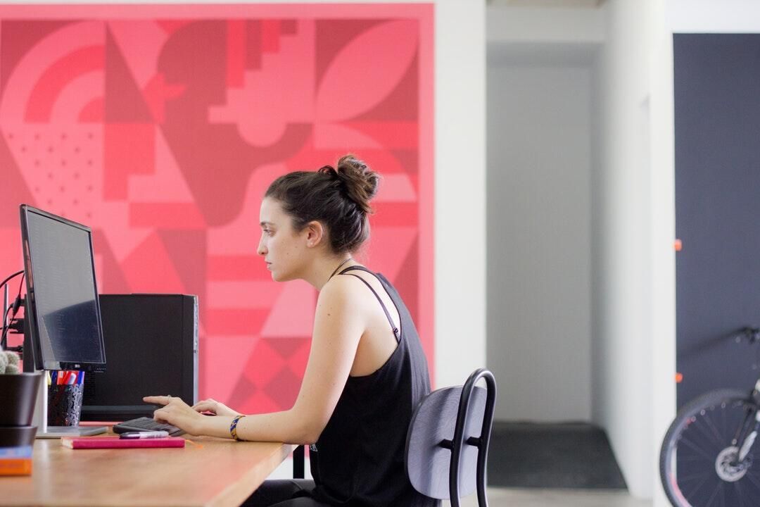 A woman is sitting at a desk in front of a computer.