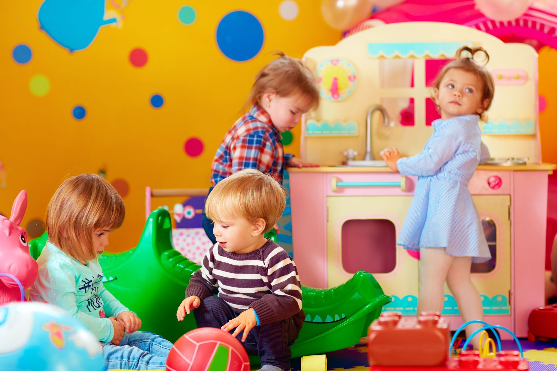 A group of children are playing with toys in a play room.