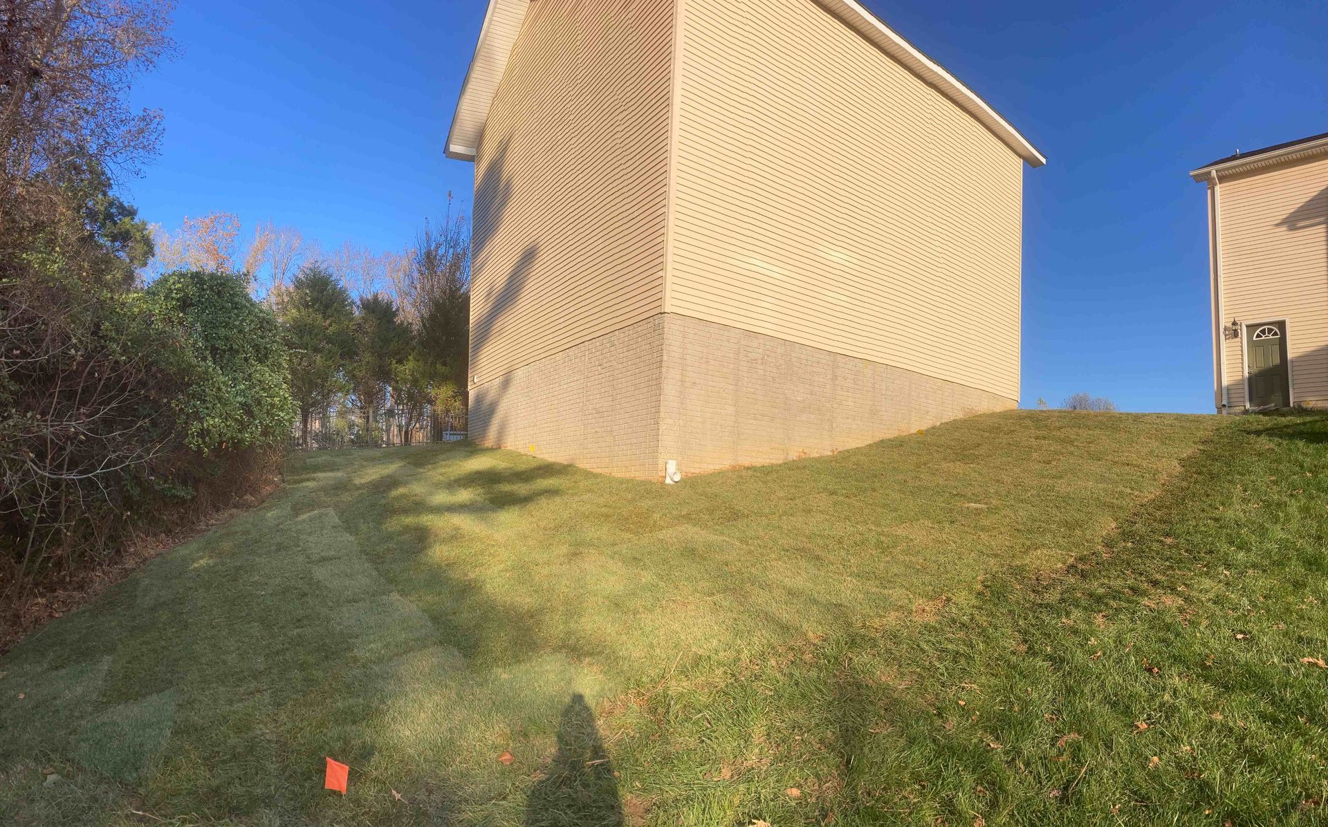 Grassy slope beside beige apartment buildings under a clear blue sky