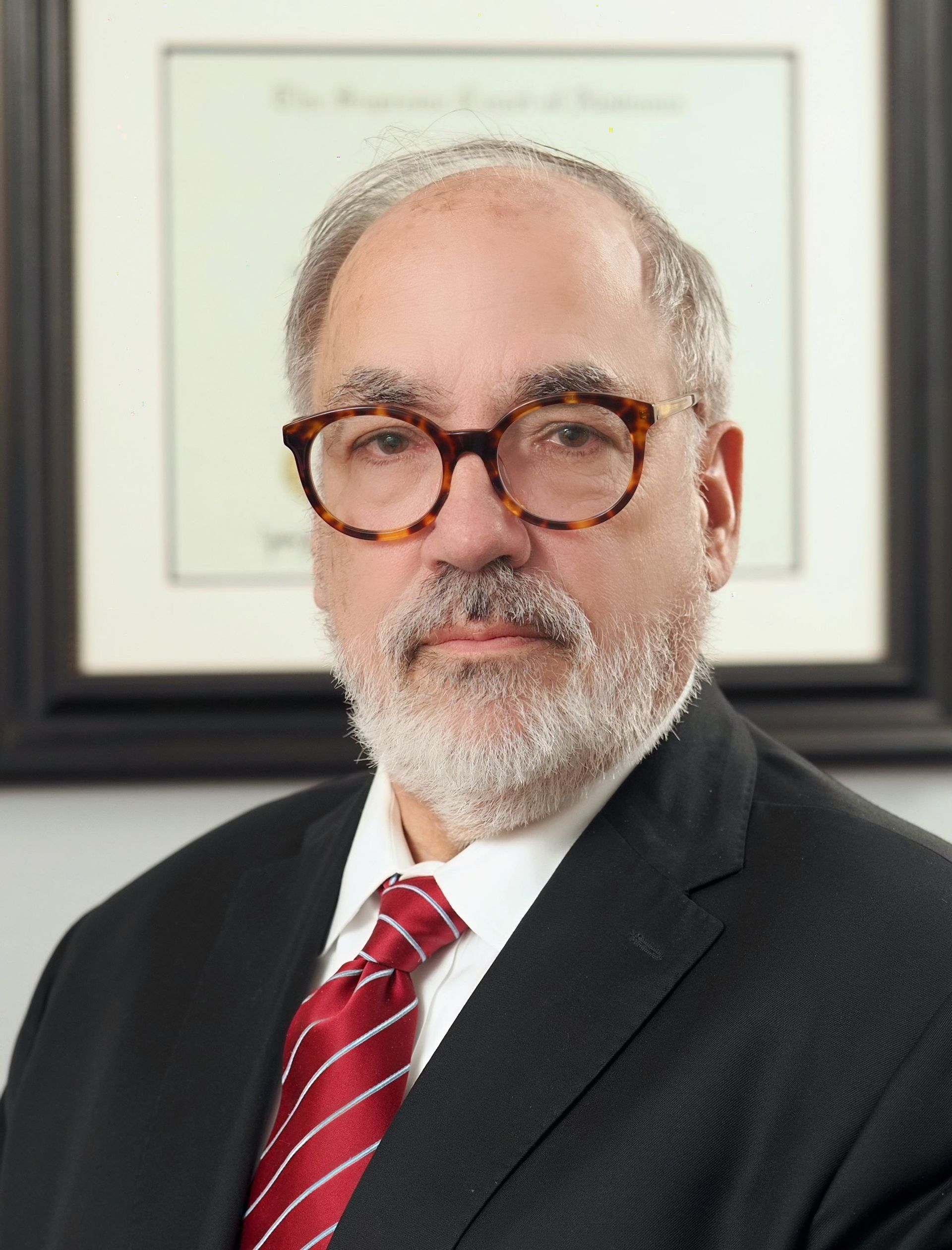 A man with glasses and a beard is wearing a suit and tie