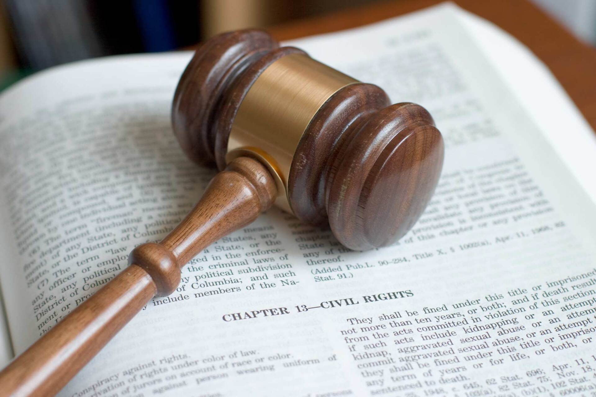 A wooden judge 's gavel is sitting on top of an open book