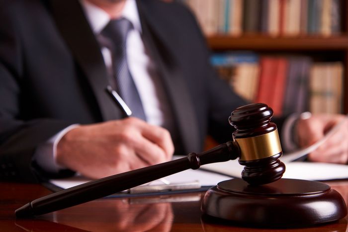 Judge gavel on desk as legal professional writes, symbolizing courtroom justice and law office.