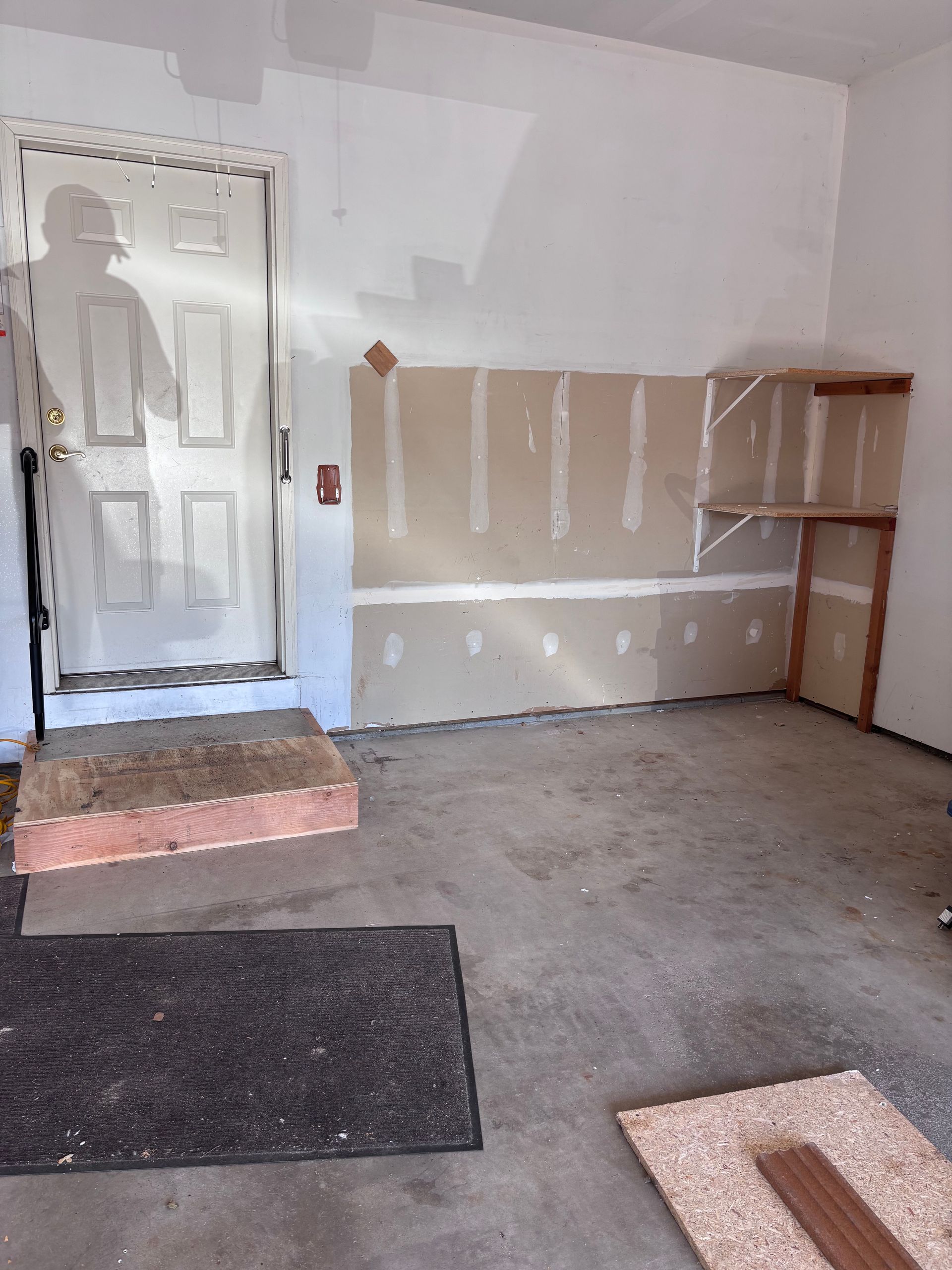 Garage interior with doorway and partially finished drywall.