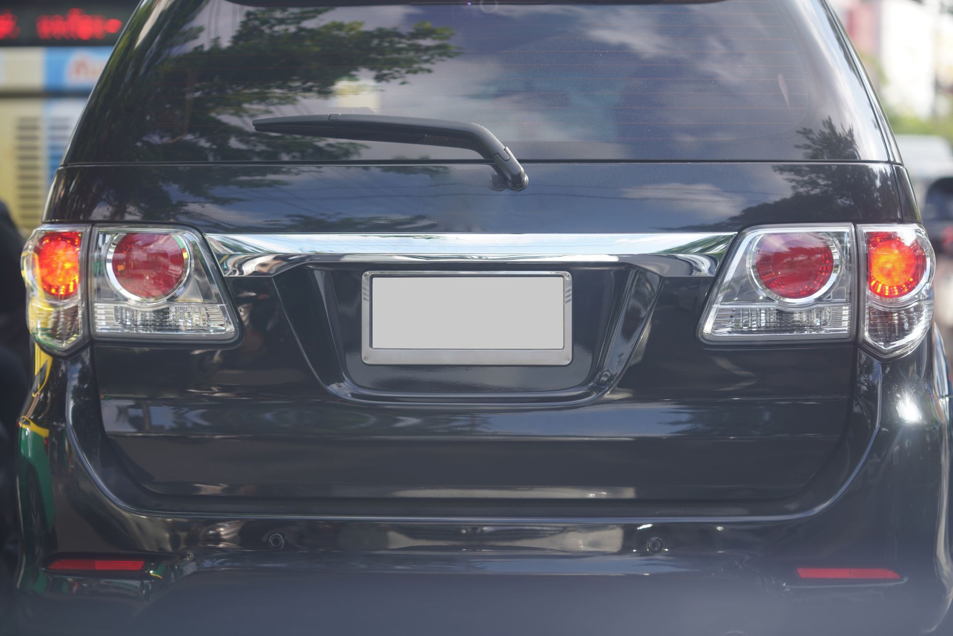 A black SUV viewed from directly behind with its red taillights on and a blank white license plate.