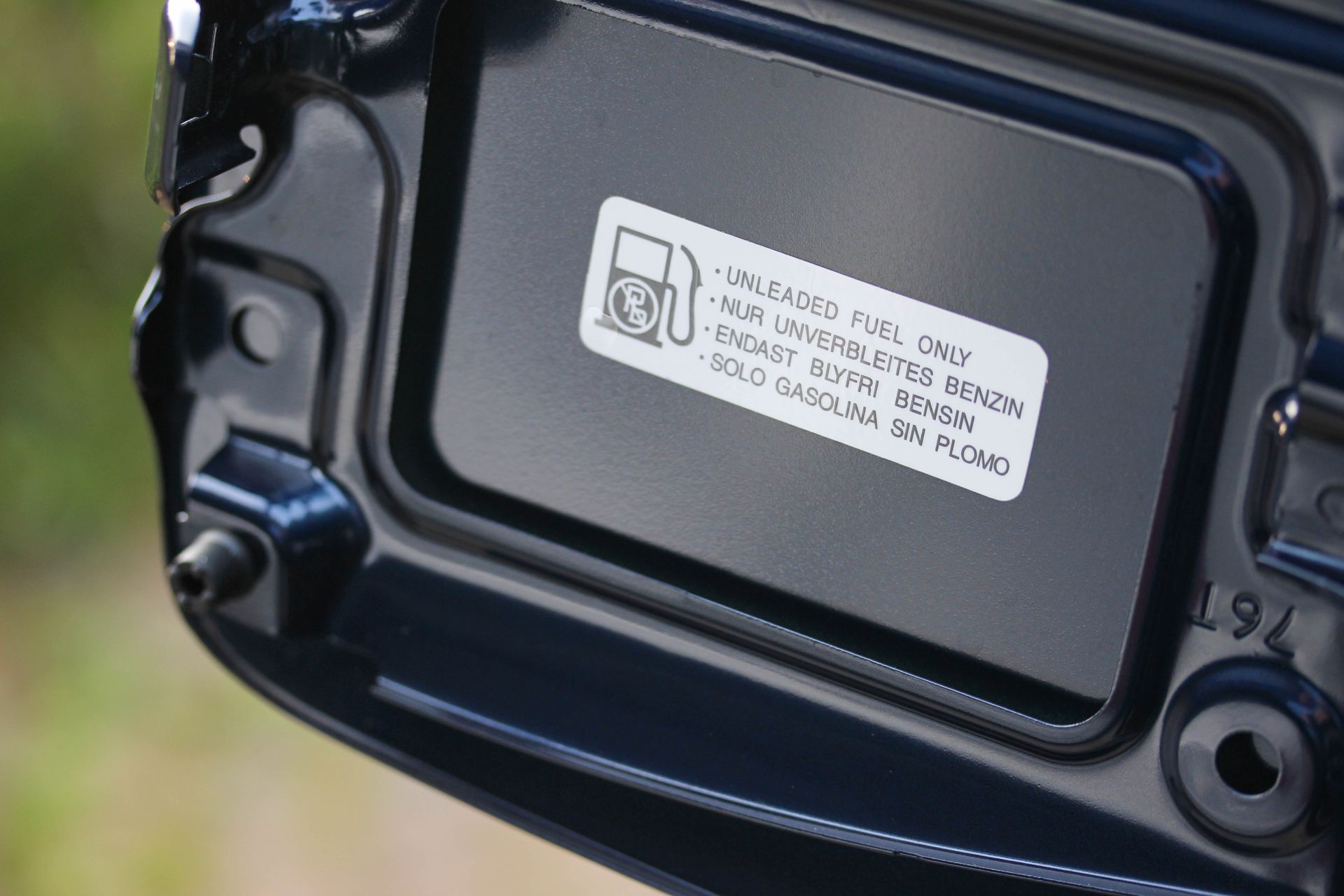 An open fuel door on a vehicle showing a sticker that reads 