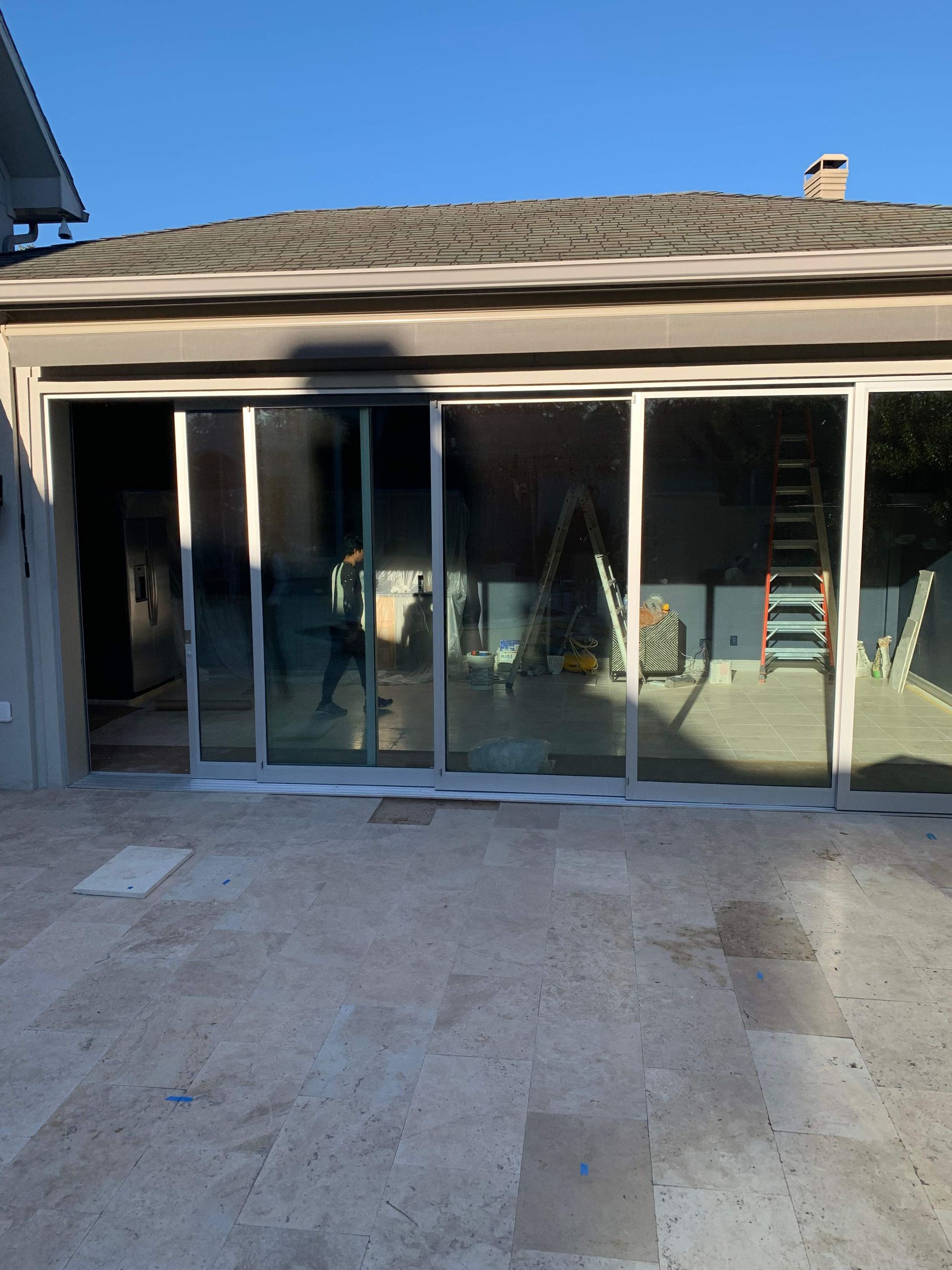 Sliding glass doors with white frames and reflective windows in a patio setting.