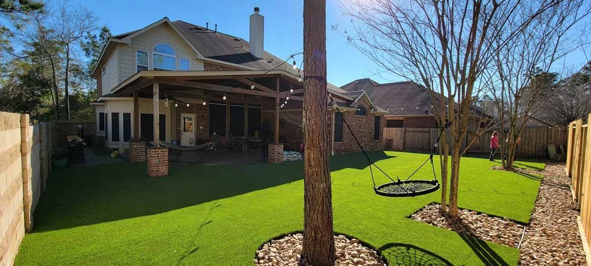 Backyard with green grass, patio, and two-story house, sunny day.