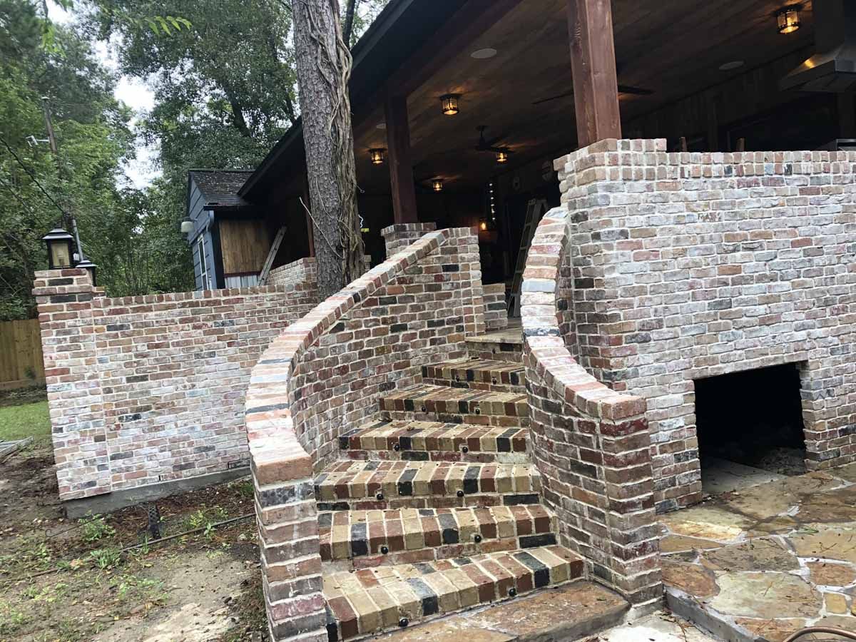 Brick staircase leading to a covered porch with an outdoor fireplace.