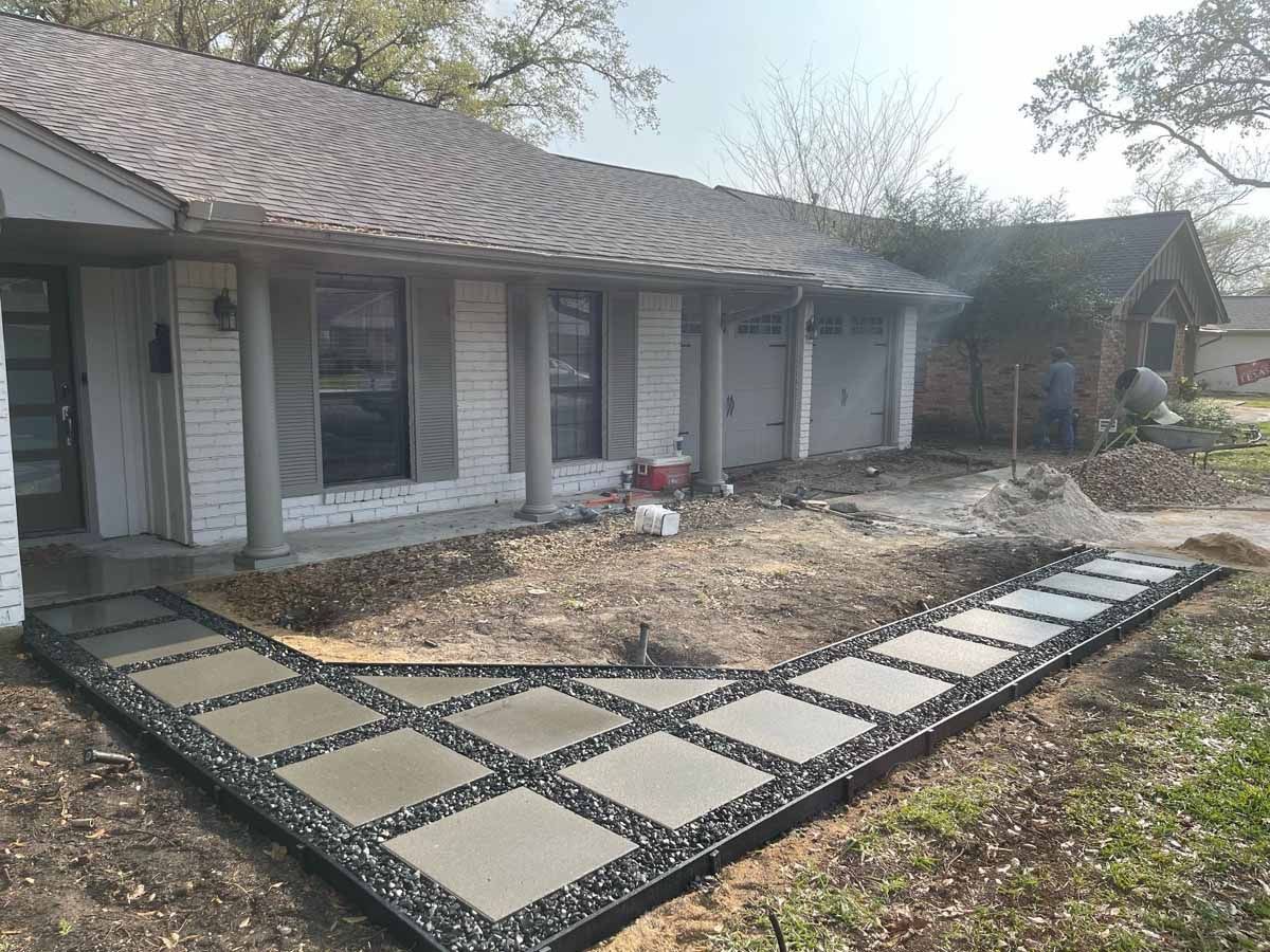 Exterior view of a house with a concrete walkway being constructed in front.