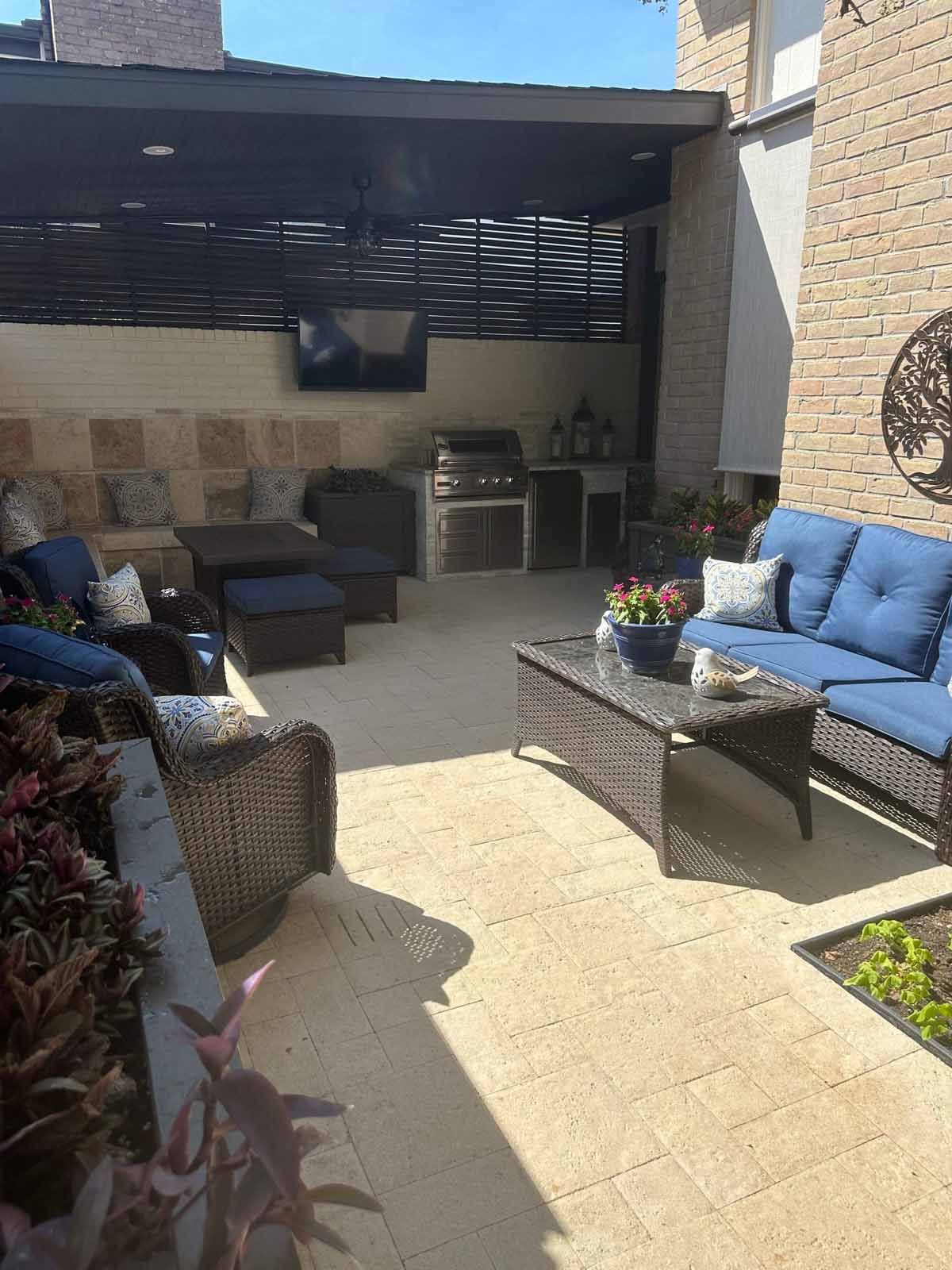 Patio with outdoor furniture, kitchen, and TV under a pergola.