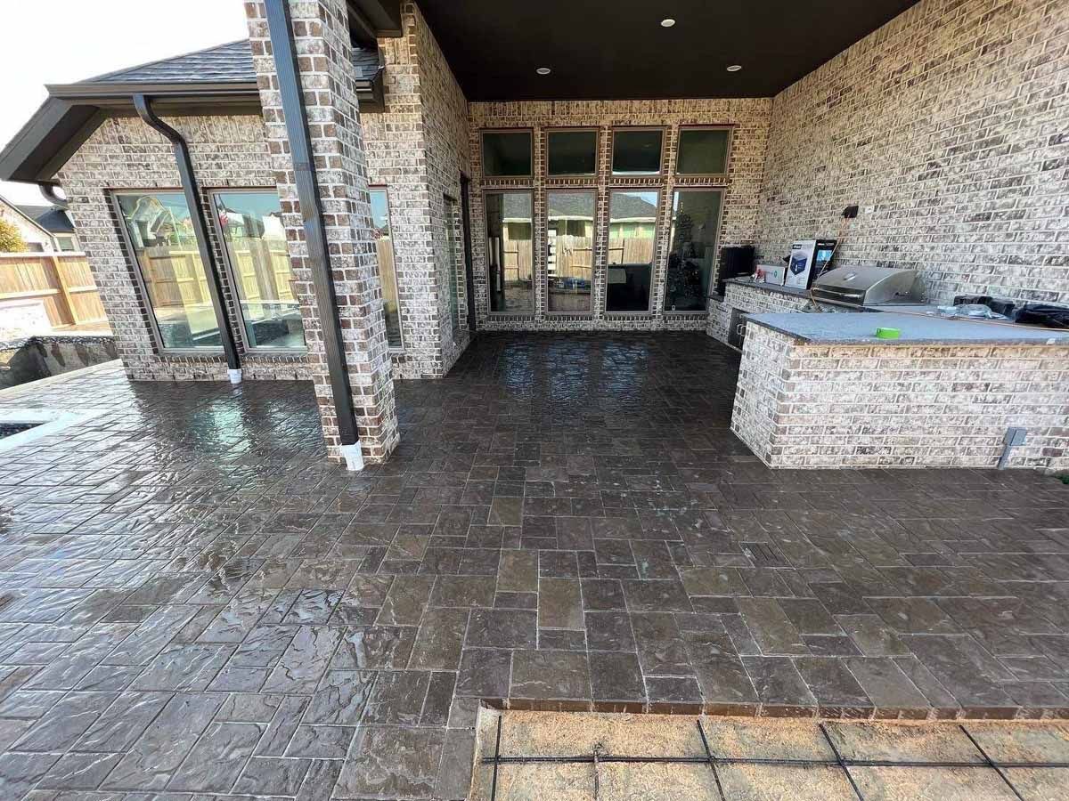 Patio with brickwork, wet surface, and outdoor kitchen.