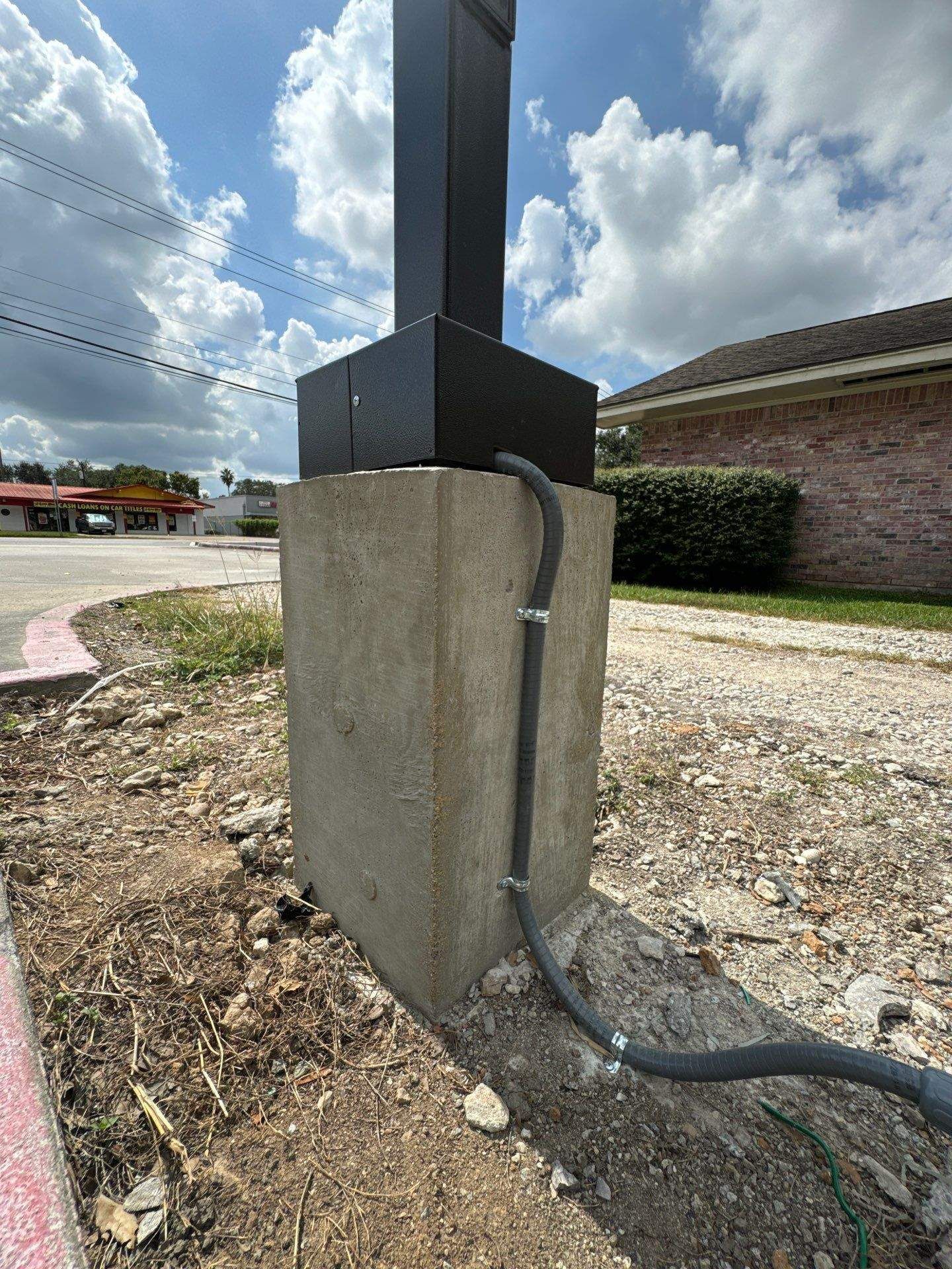 Concrete pillar supports a sign post with electrical conduit attached.