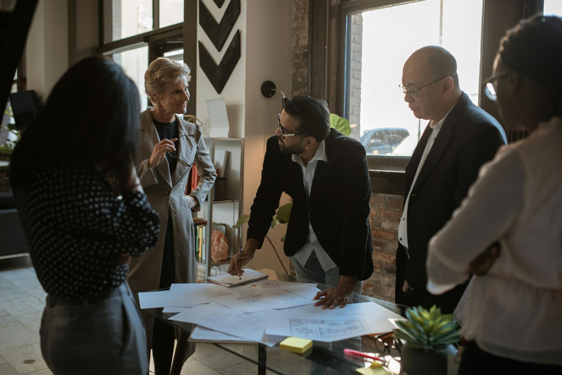 Team gathered around a table reviewing papers in a bright office meeting room
