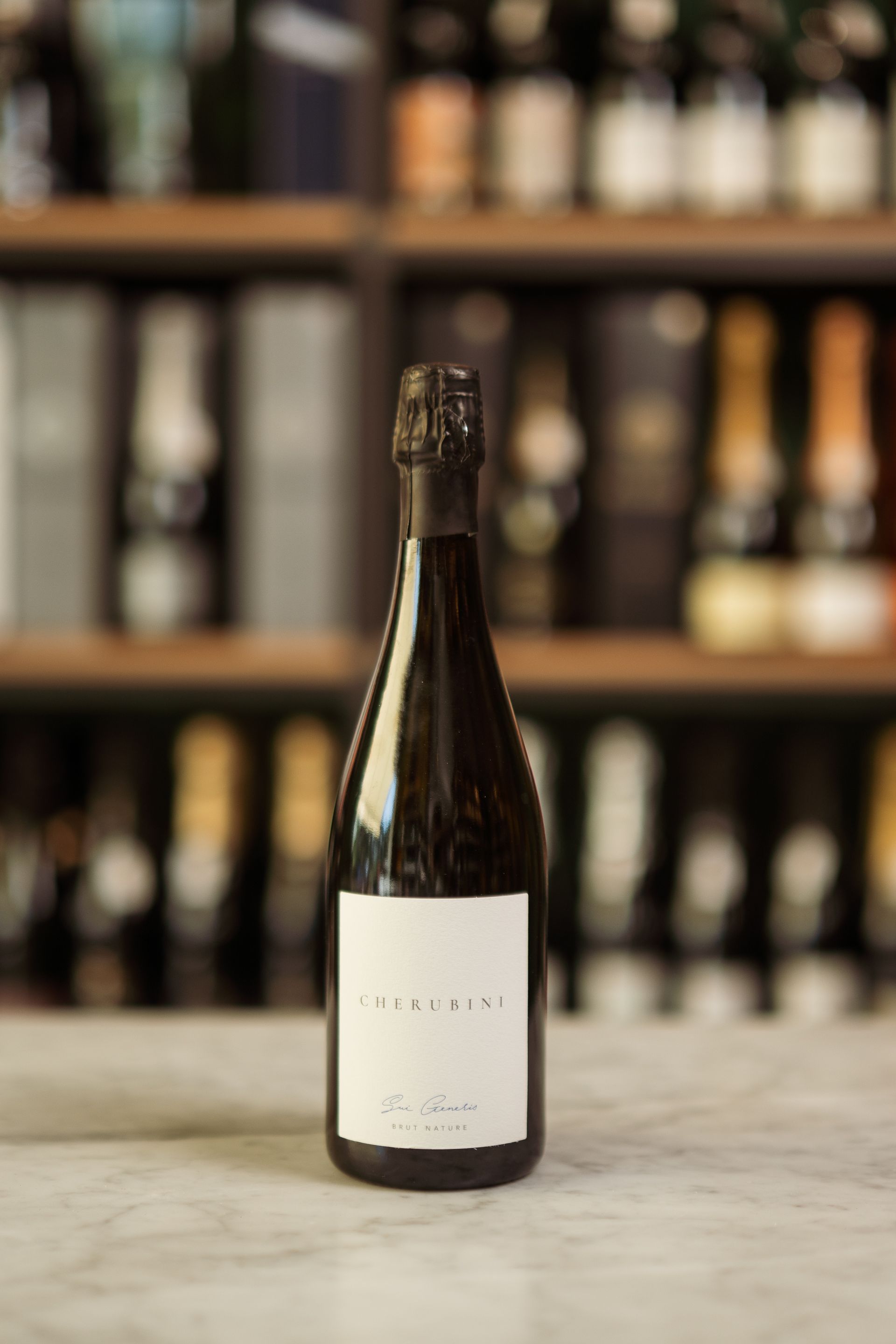 Una bottiglia di vino è appoggiata su un tavolo davanti a uno scaffale.