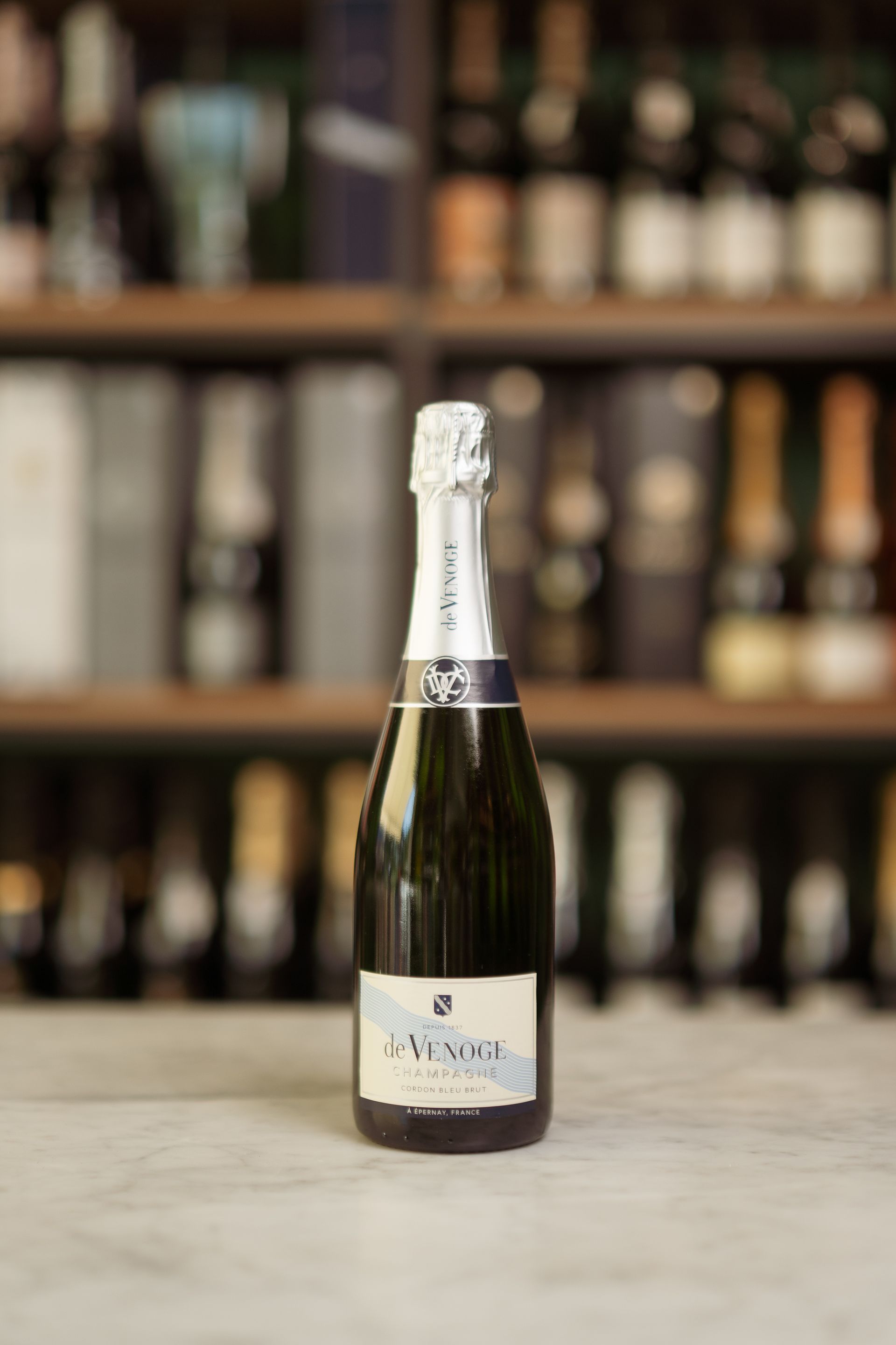 Una bottiglia di champagne è appoggiata su un tavolo davanti a uno scaffale.