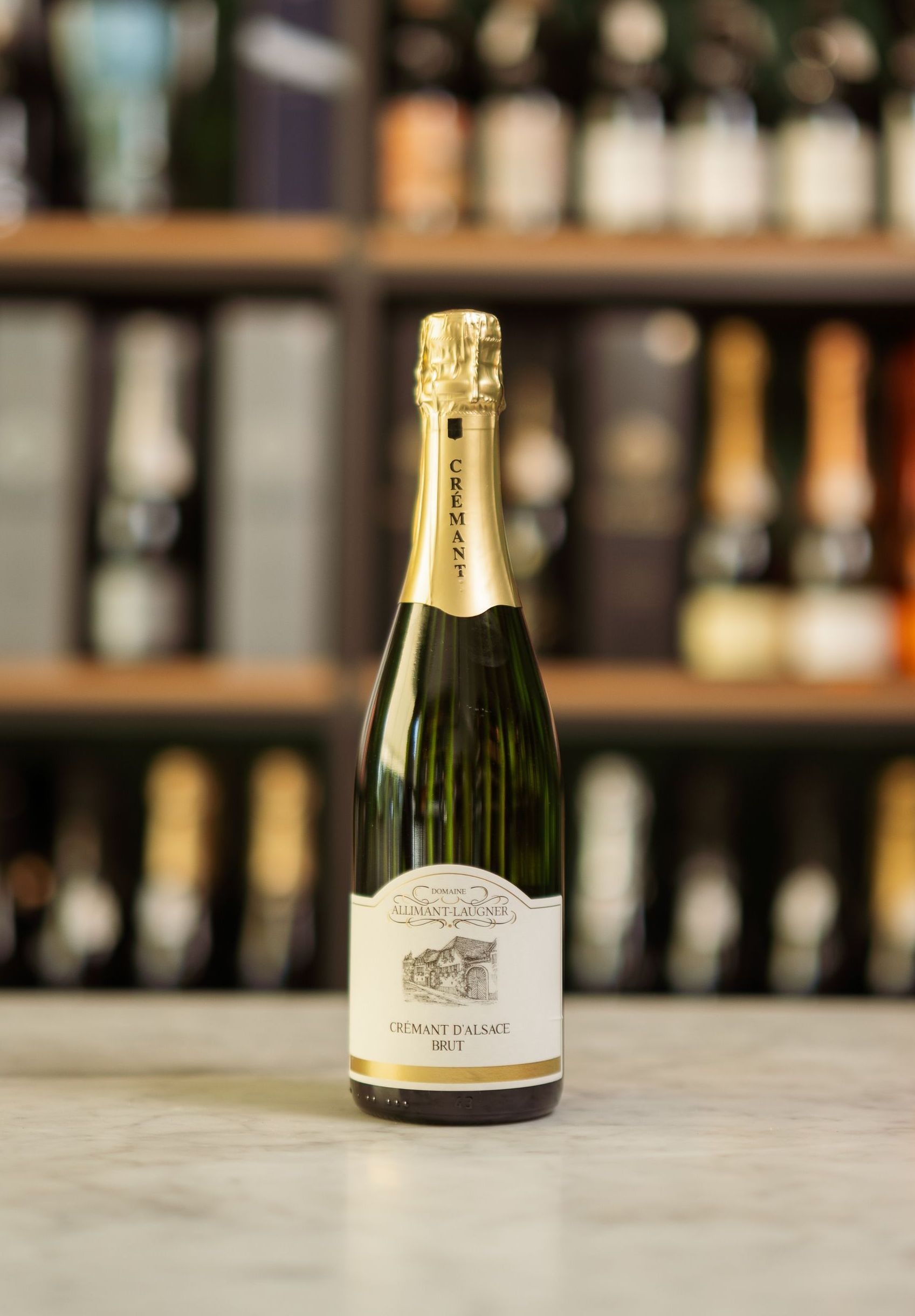 Una bottiglia di champagne è appoggiata su un tavolo davanti a uno scaffale.