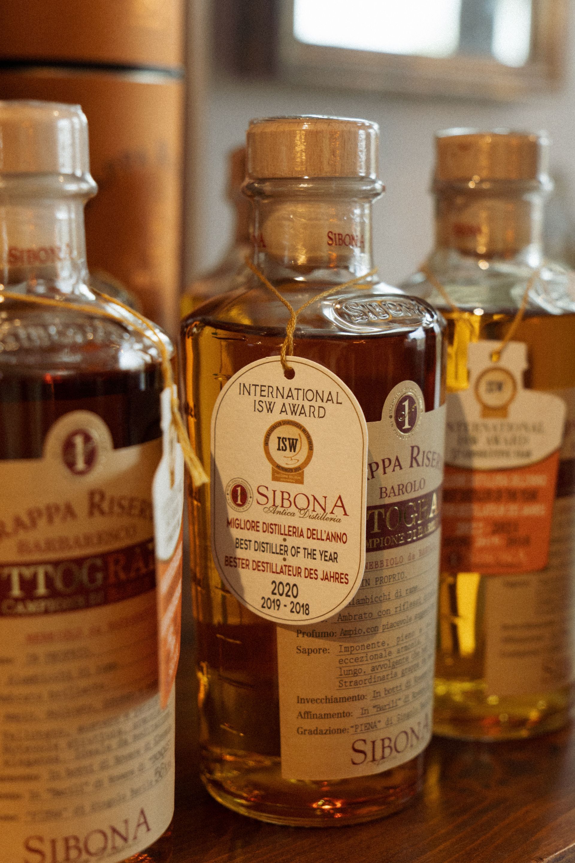 Una fila di bottiglie di alcolici è appoggiata su un tavolo di legno.