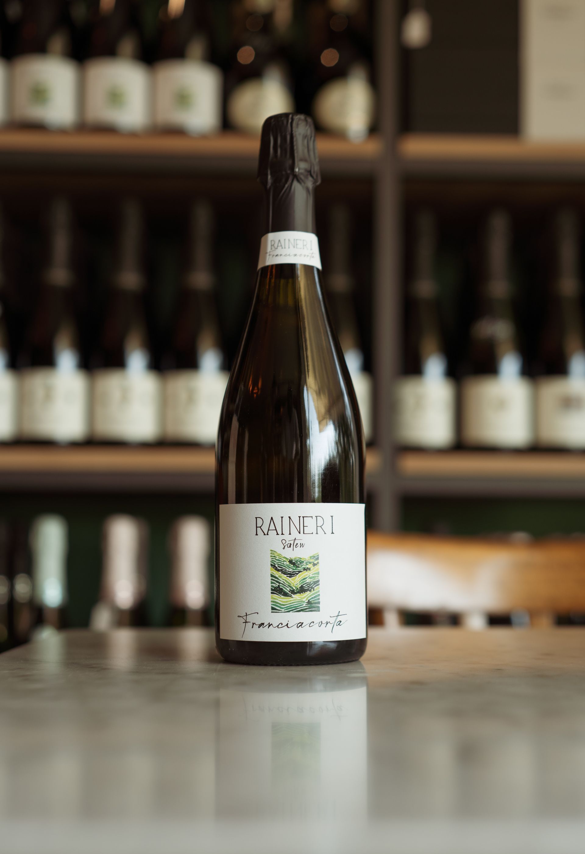 Una bottiglia di vino è appoggiata su un bancone di fronte a uno scaffale di bottiglie di vino.