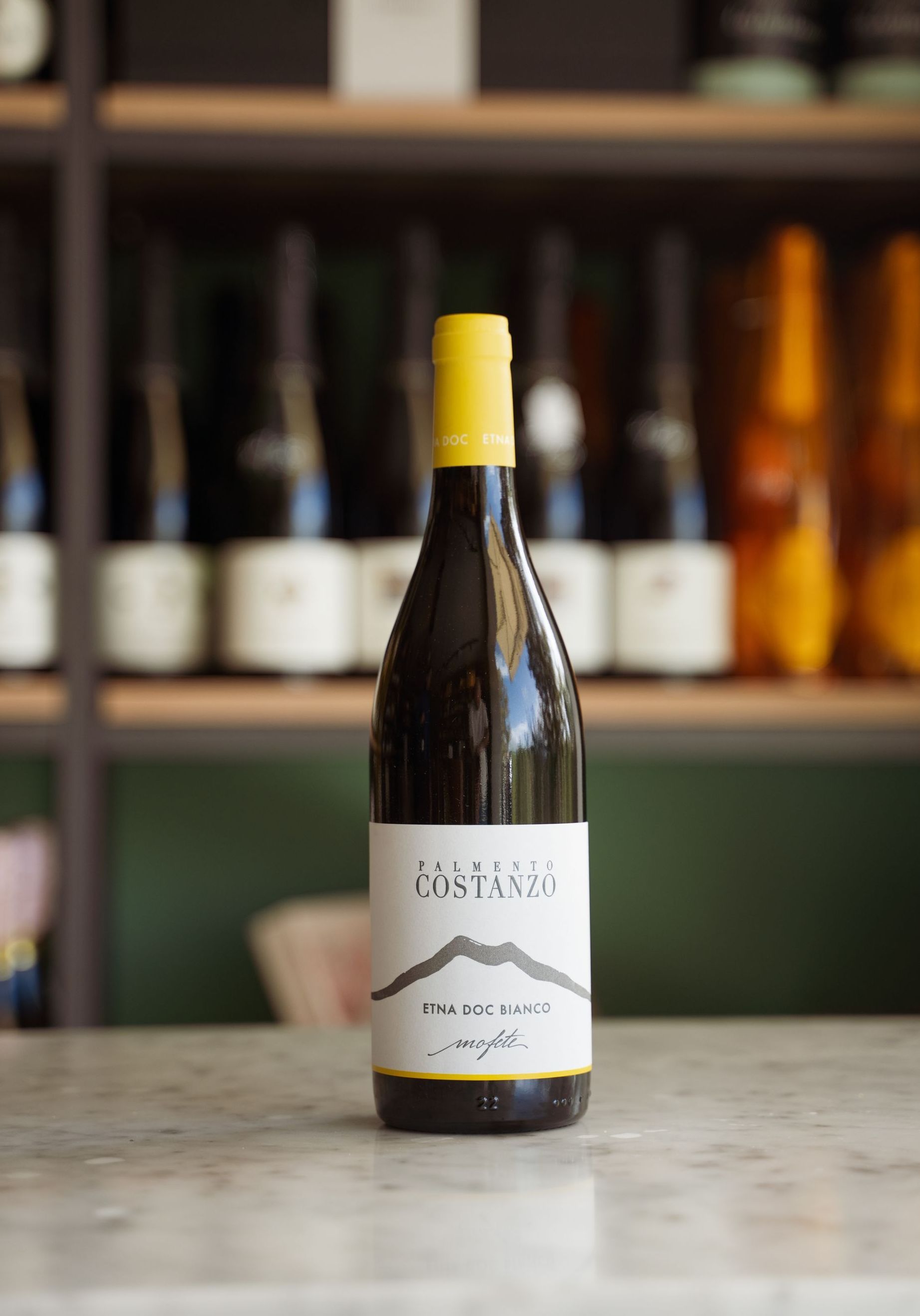 Una bottiglia di vino con un tappo giallo è appoggiata su un tavolo.