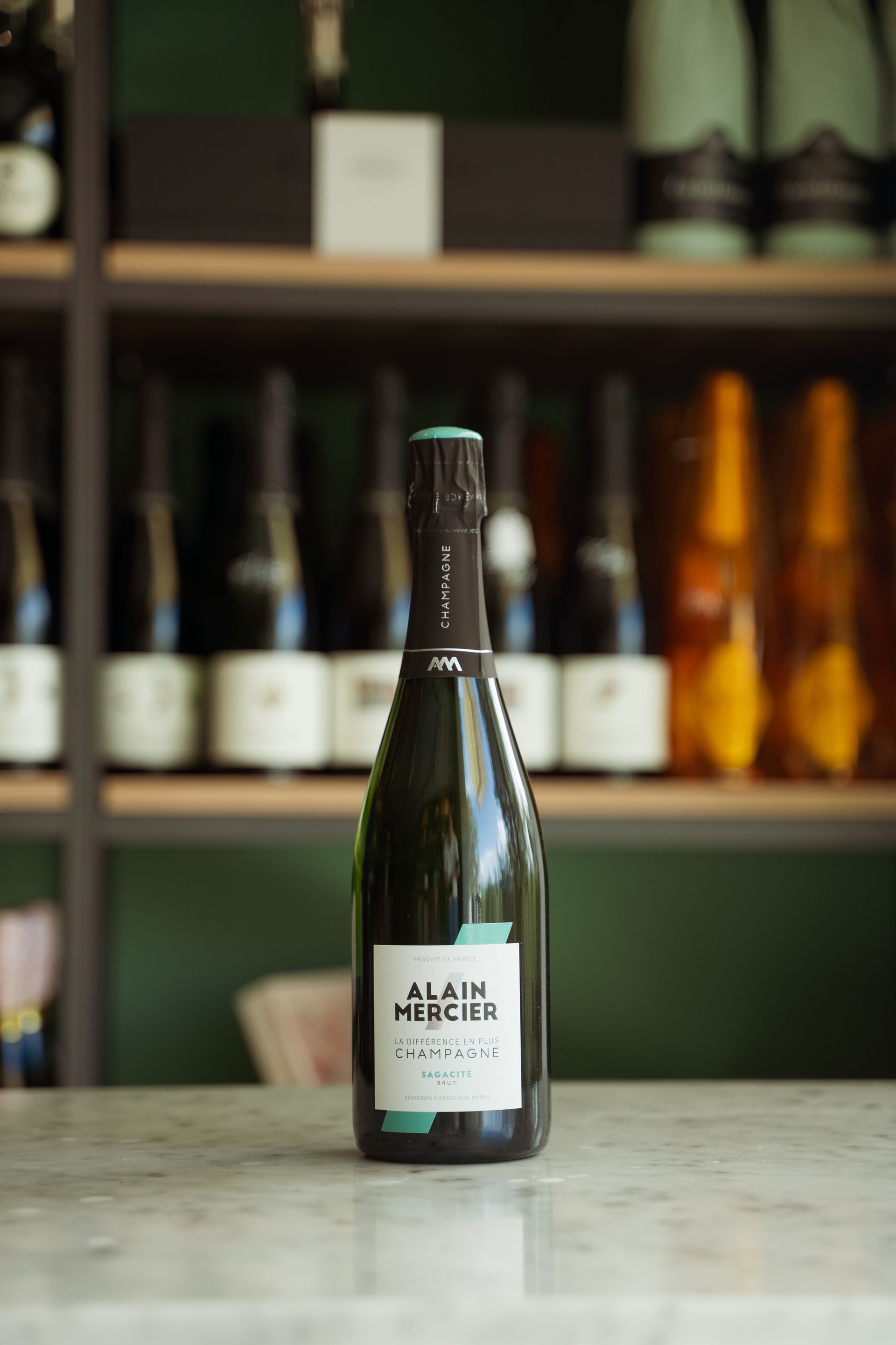 Una bottiglia di champagne è appoggiata su un bancone davanti a uno scaffale.